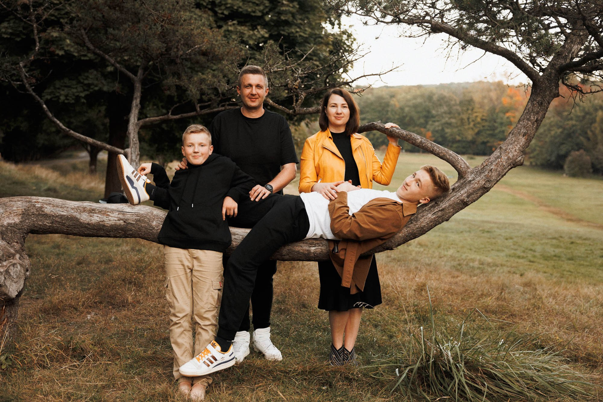 Family of four sitting together on a large tree branch