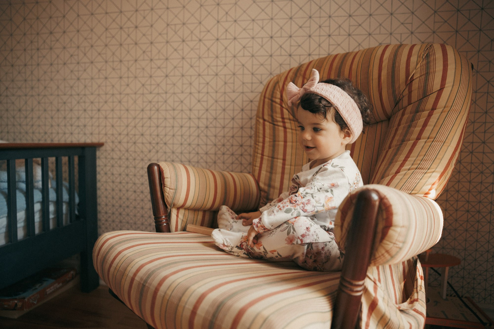 Toddler sitting in a striped armchair during an at-home family session