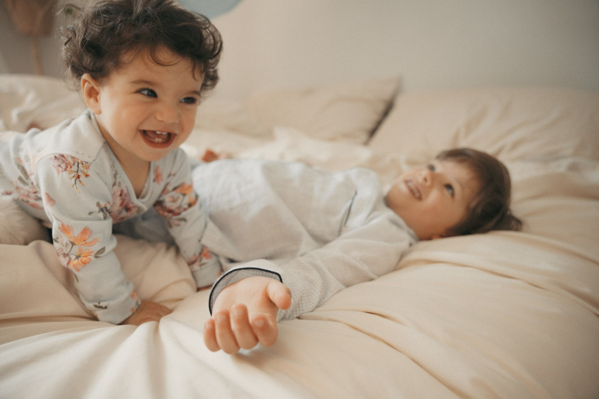 Older brother lying beside a newborn baby on the family bed