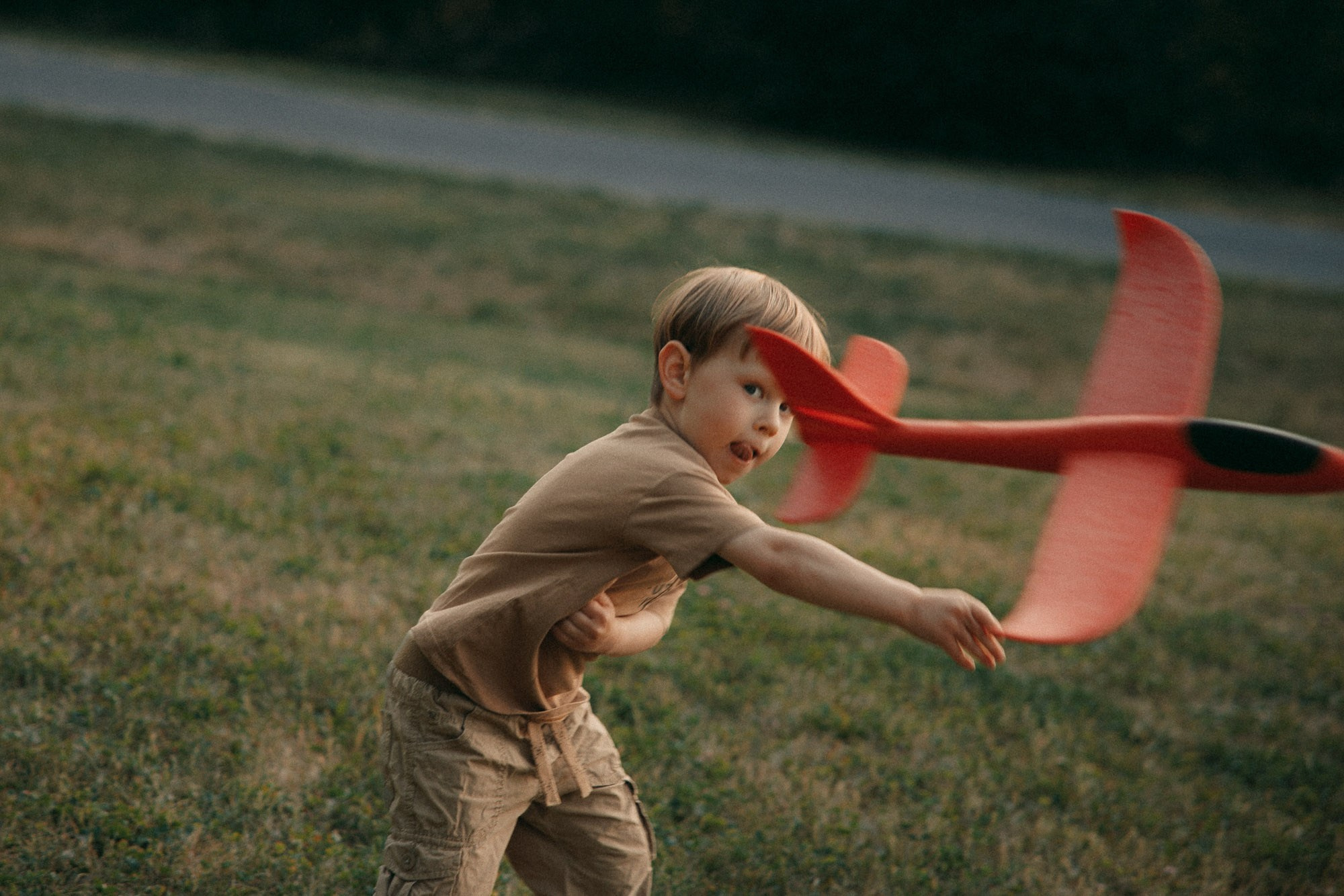 Young boy launching a red toy airplane during an outdoor family session
