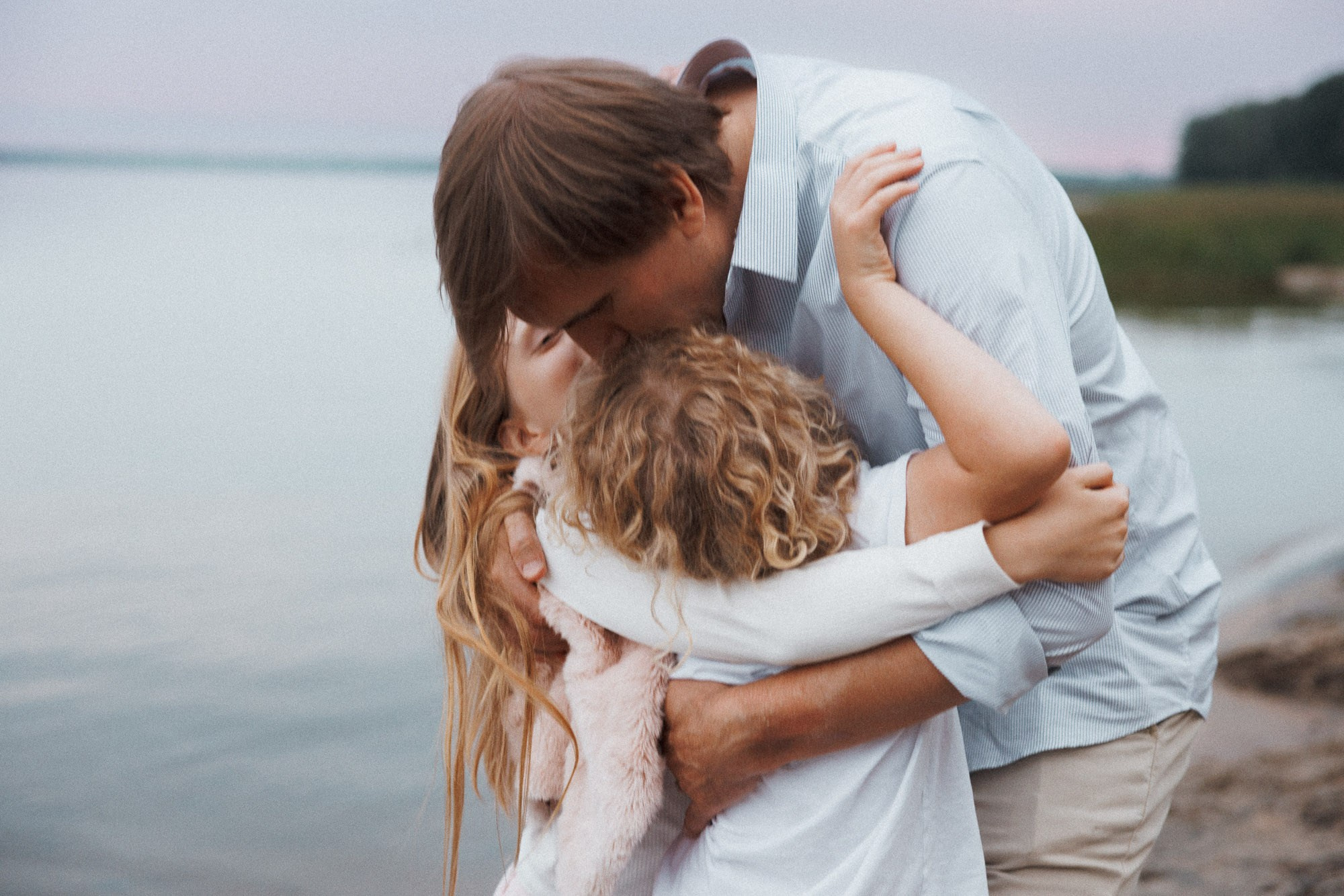 Parents embracing their child during a relaxed beach family session