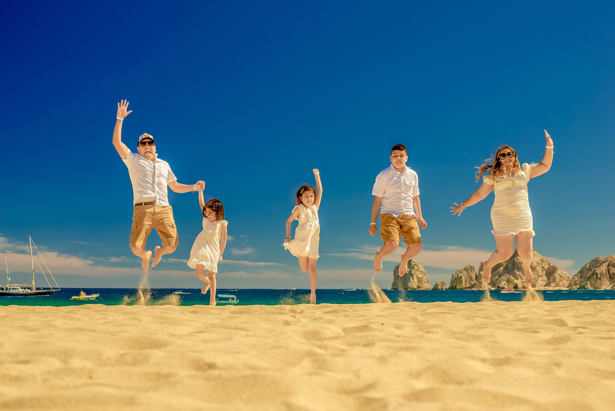 Fun family photoshoot in Los Cabos – family of five jumping together on the beach, joyful and playful destination beach photography
