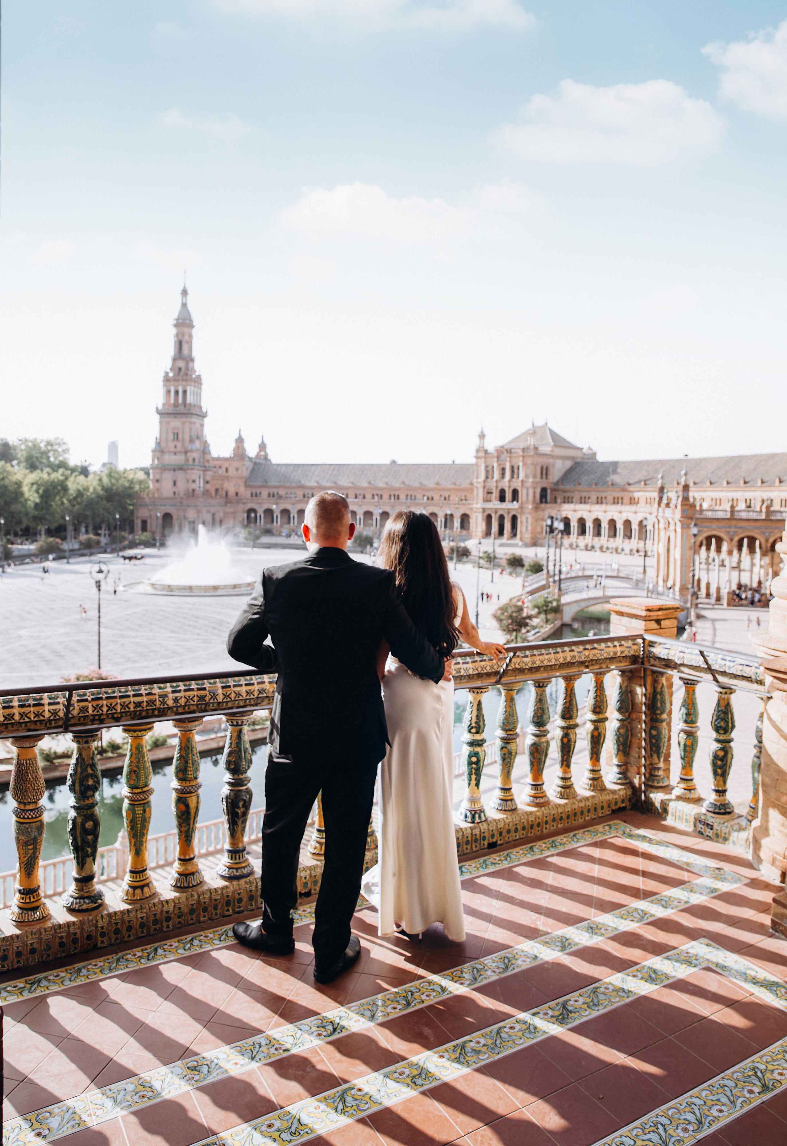 Romantic wedding photo in Sevilla, Spain — a bride and groom stand hand in hand overlooking the breathtaking Plaza de España, capturing the timeless beauty and elegance of a wedding photoshoot in Seville. Perfect inspiration for couples searching for destination wedding photography in Spain.