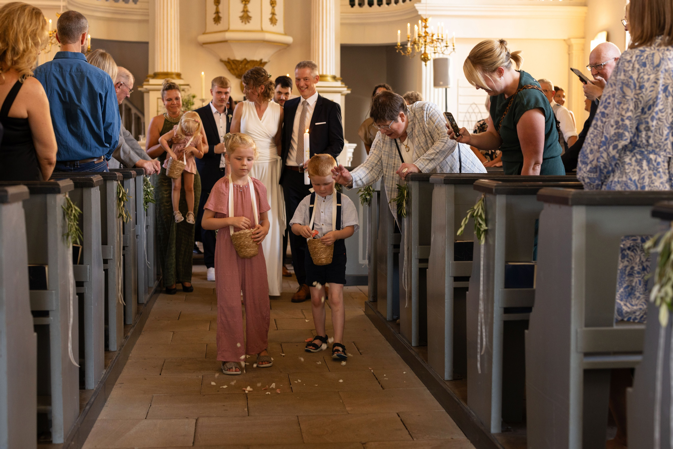 Blumenkinder streuen Blüten während der kirchlichen Trauung in Berge.“