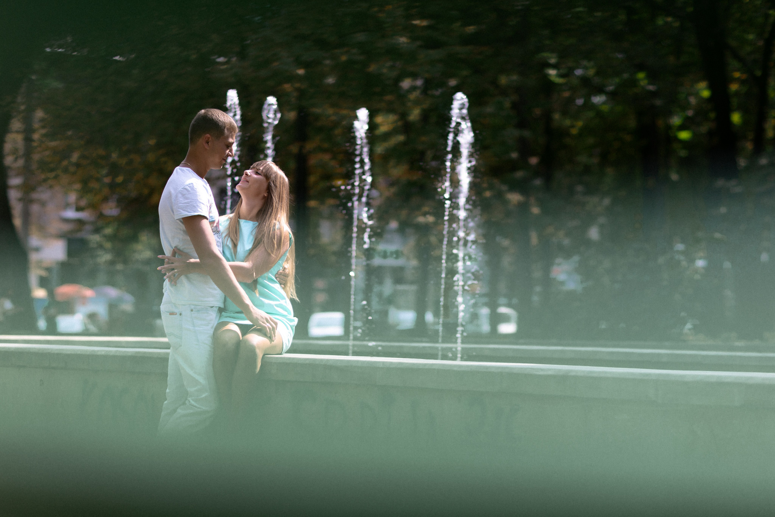 Парень девушка в объятиях смотрят друг на друга у фонтана влюбленные 