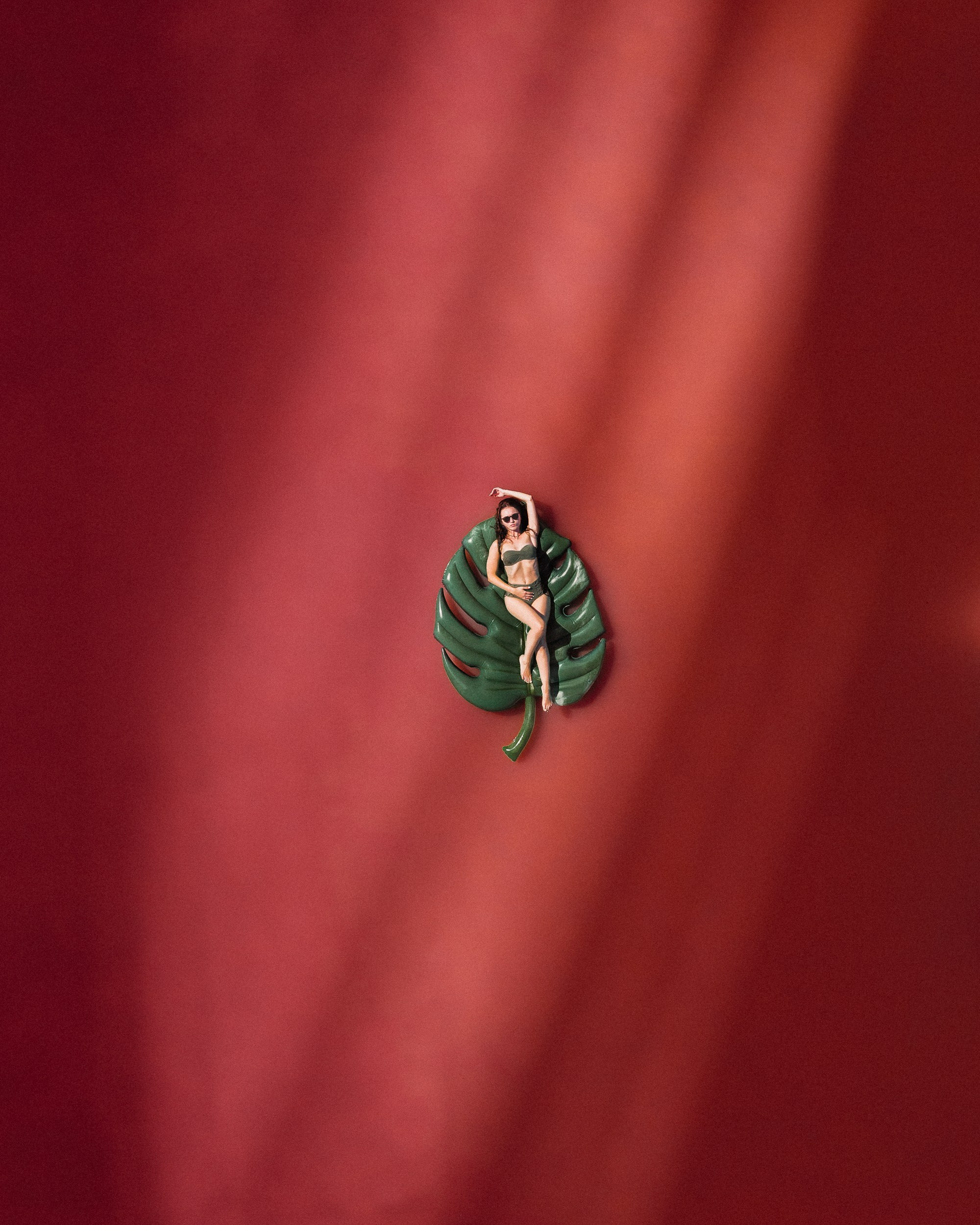 A drone photo of a pink lake with a woman floating on top of the lake 