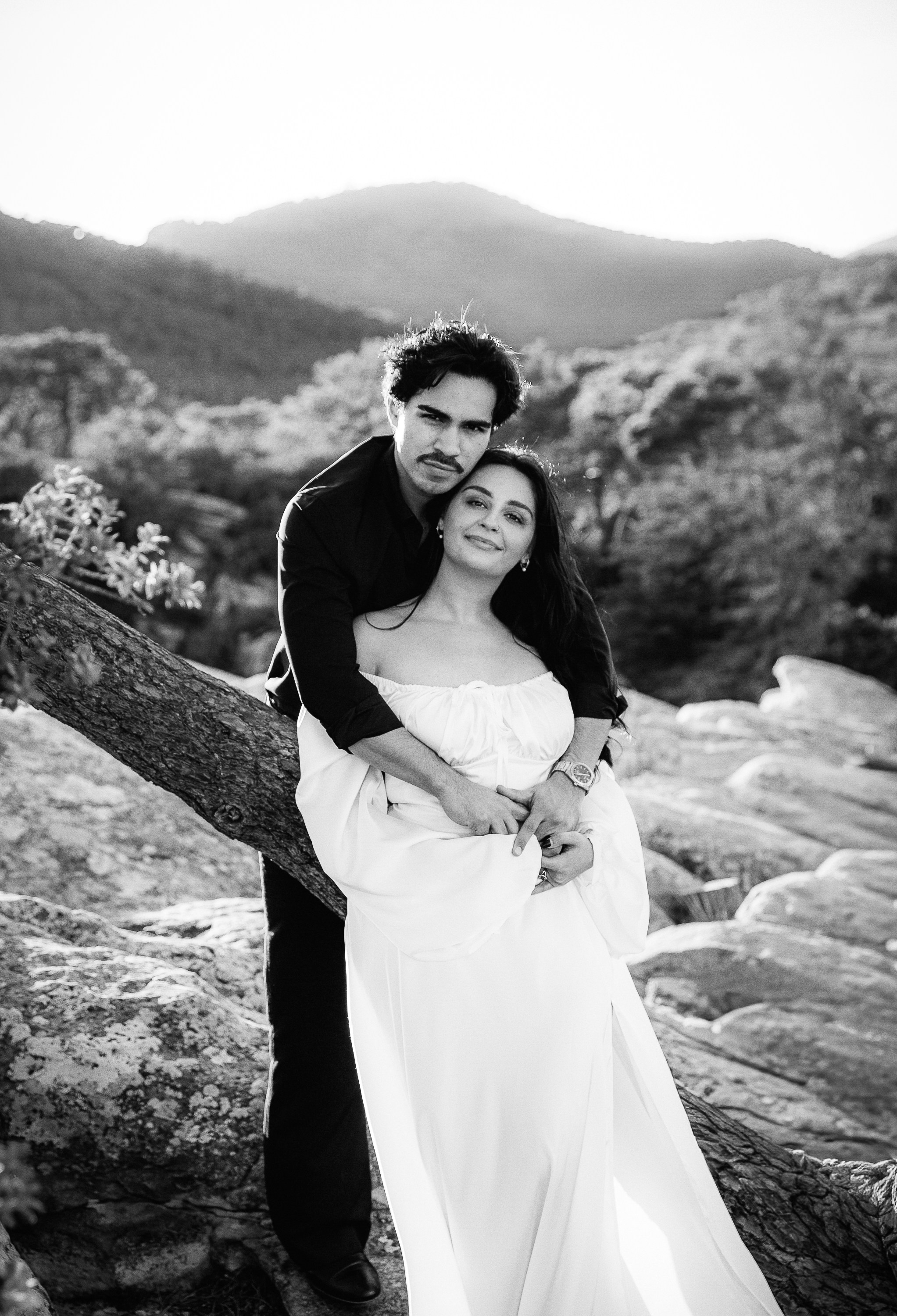 Engagement photoshoot in València, Spain, featuring a couple embracing on rocky cliffs in a timeless black-and-white portrait, surrounded by dramatic mountain landscapes and soft natural light — a romantic engagement and wedding love story image ideal for engagement photography, pre-wedding photoshoots, elopements, and professional wedding photography in València and across Spain.