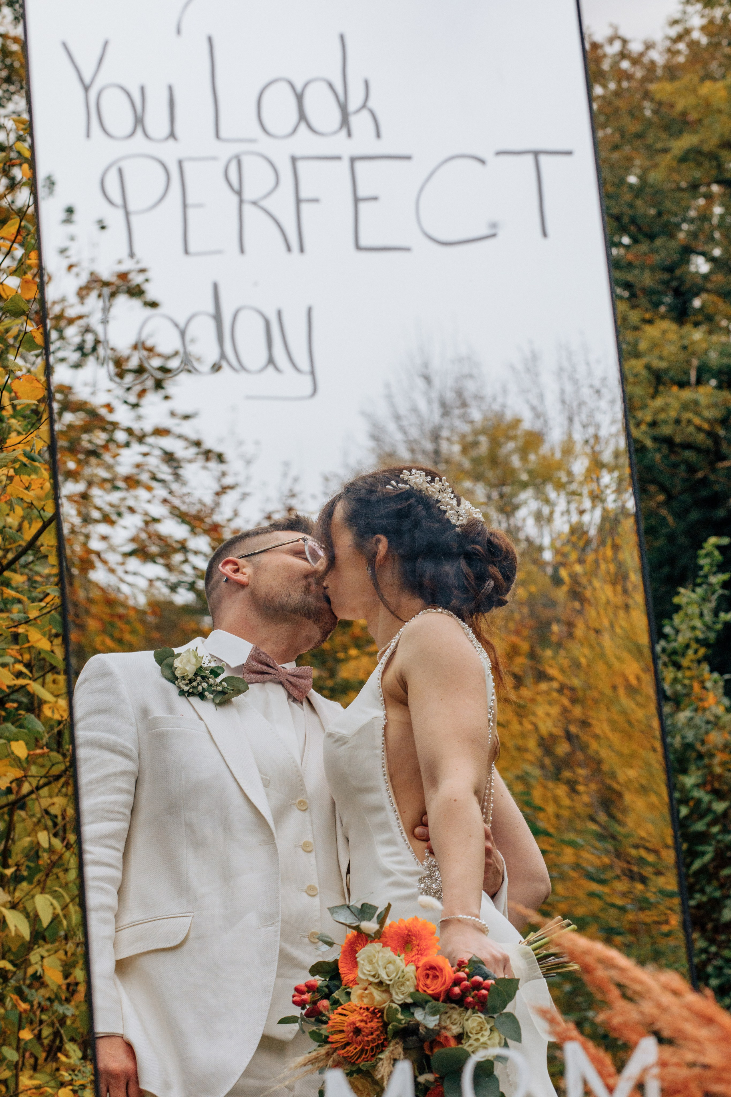 Die Reflexion des sich küssenden Brautpaares auf einem Spiegel mit süßer Textschrift.