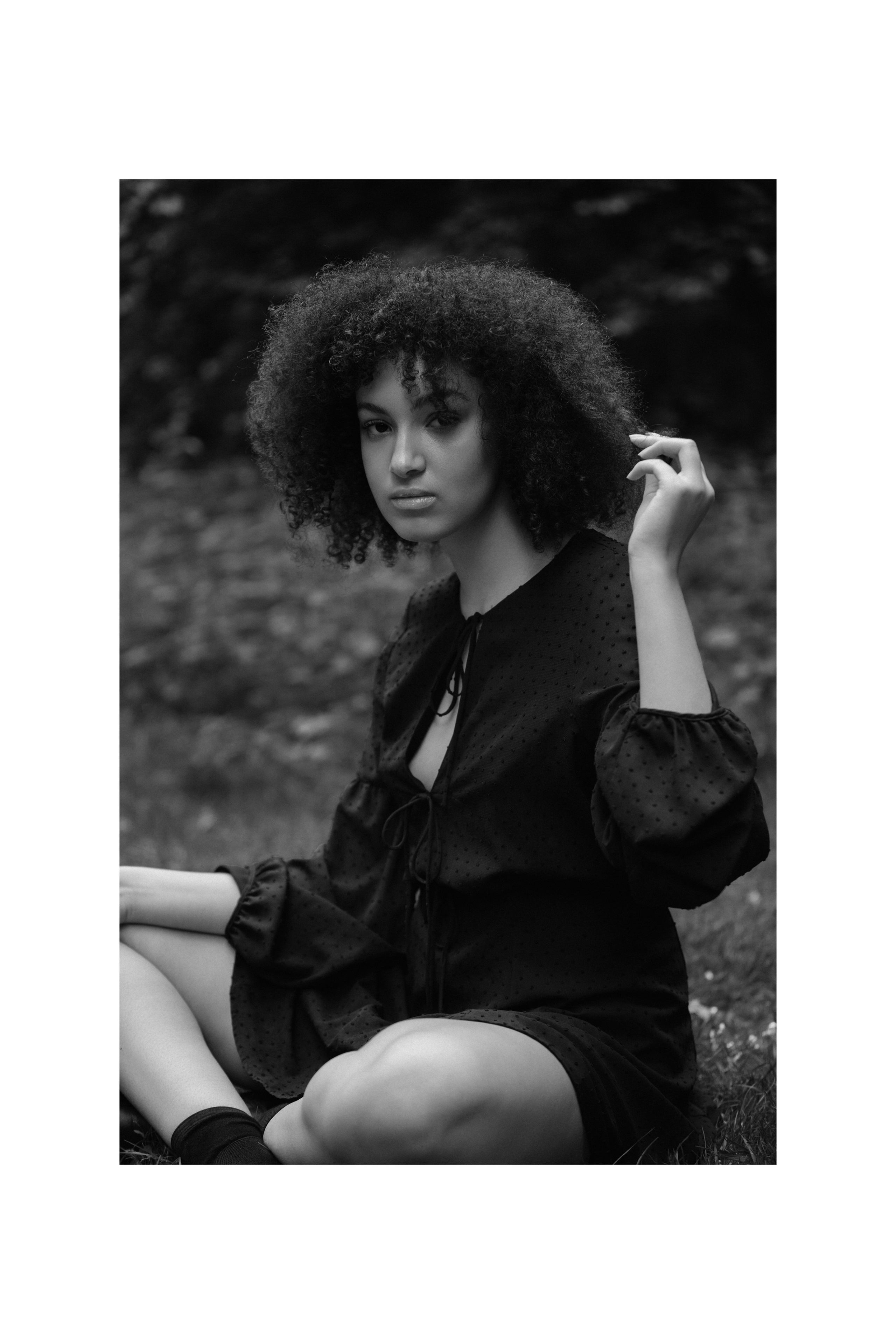 Schwarzweiß-Porträt, Frau sitzt und berührt ihr Haar