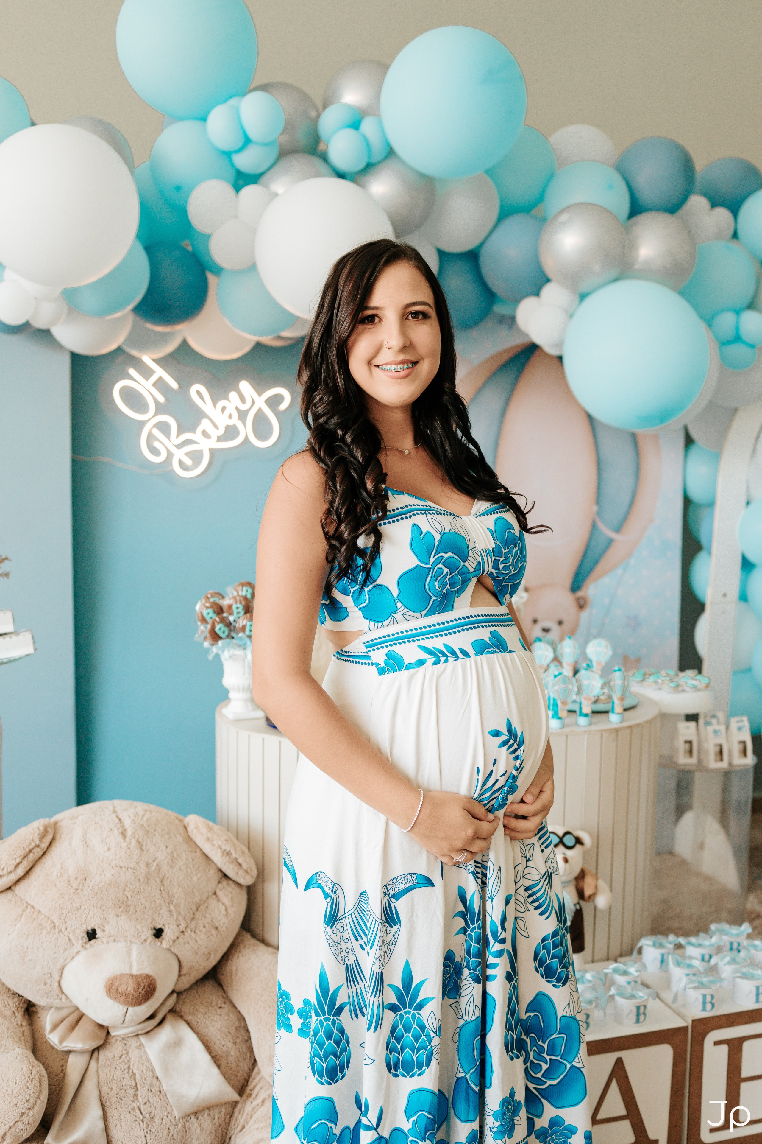 Casal posando junto à decoração com balões azuis no chá de bebê em Barra Bonita.