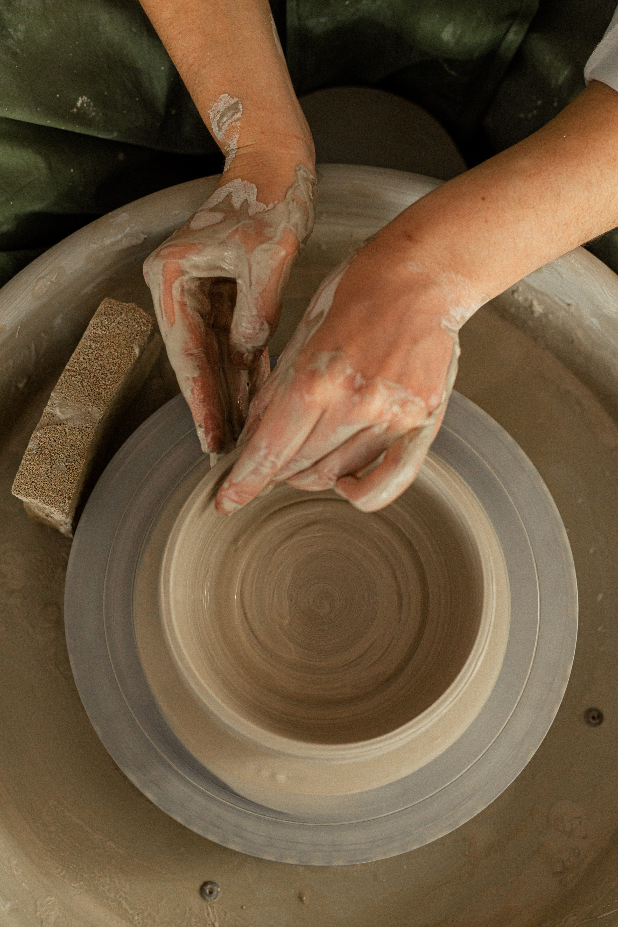 Tiernas manos femeninas en el proceso de hacer una taza en un torno de alfarería