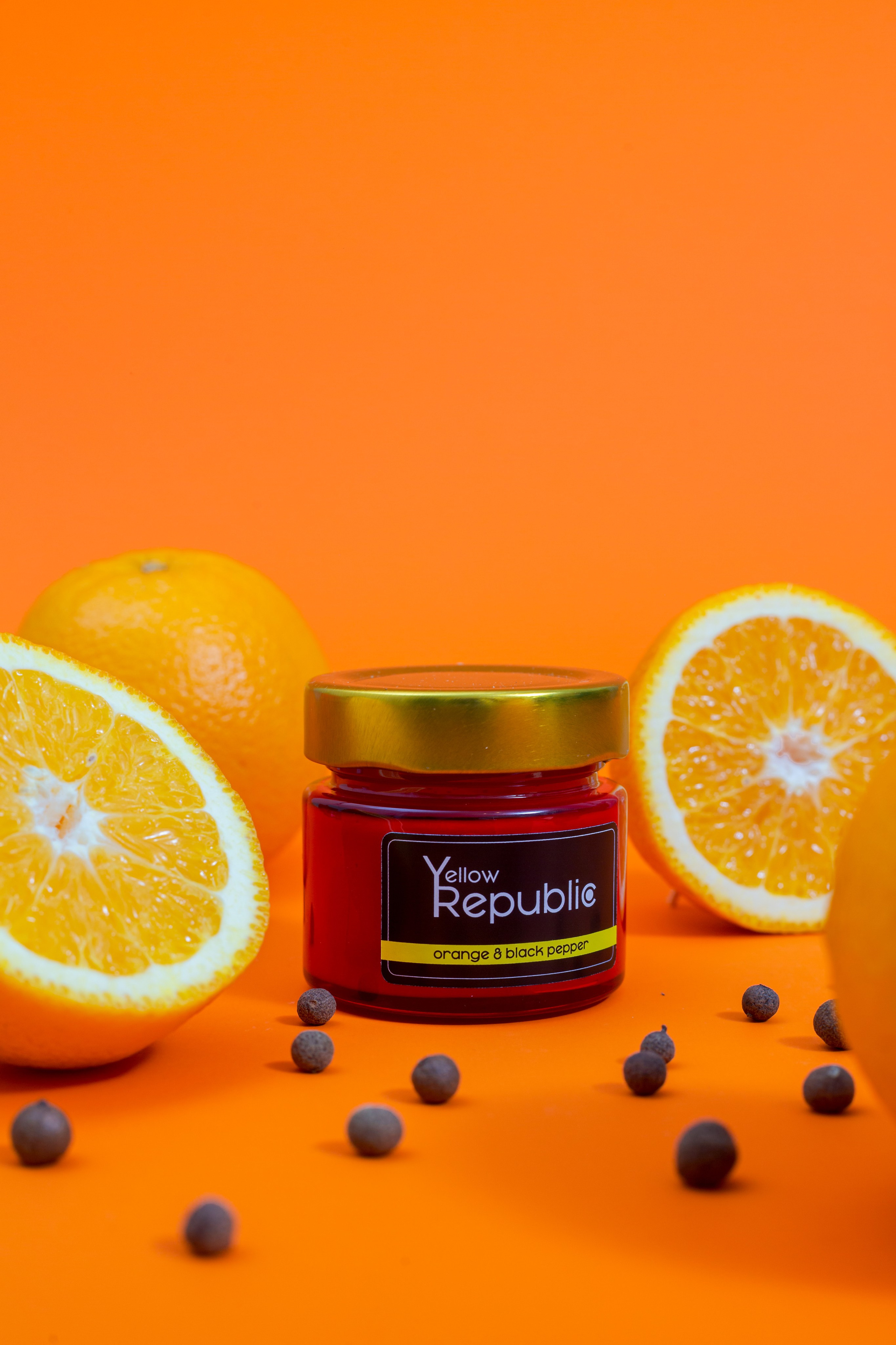 Tarro de vela sobre fondo naranja con naranja cortada