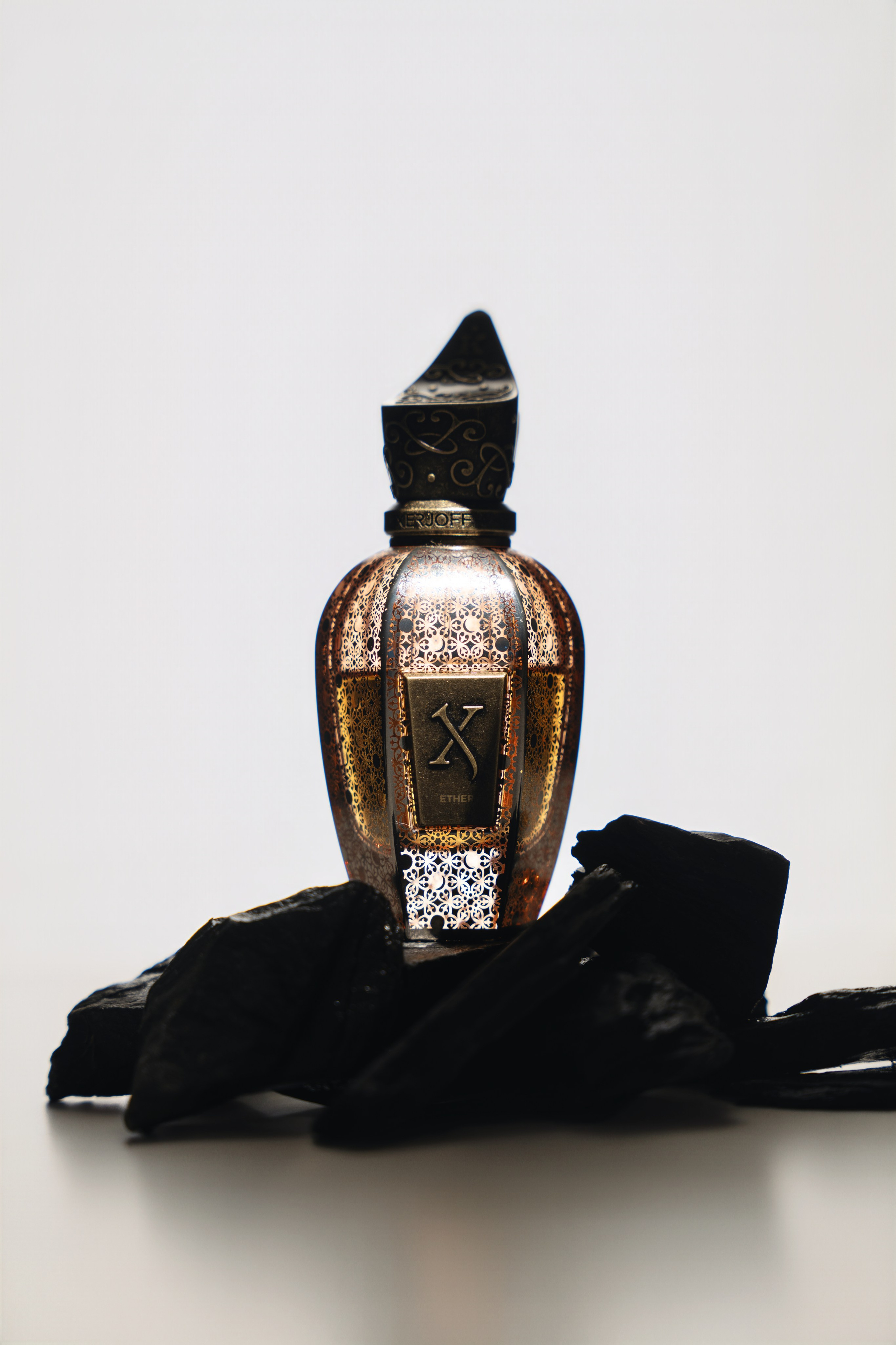 Luxury fragrance bottle reflection on black surface — minimal cinematic still life.