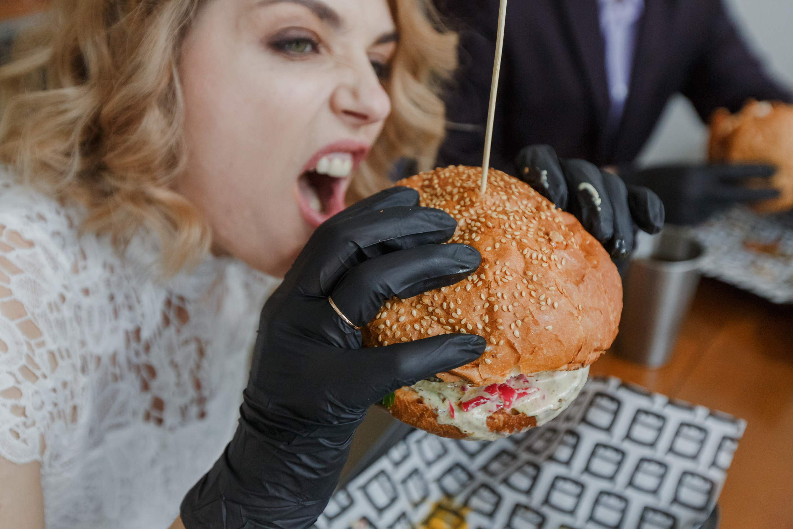 Valientes recién casados ​​comen hamburguesas con guantes negros. Fotógrafo de retrato, familia y reportajes en Valencia | España | Europa Vitalii Lumier