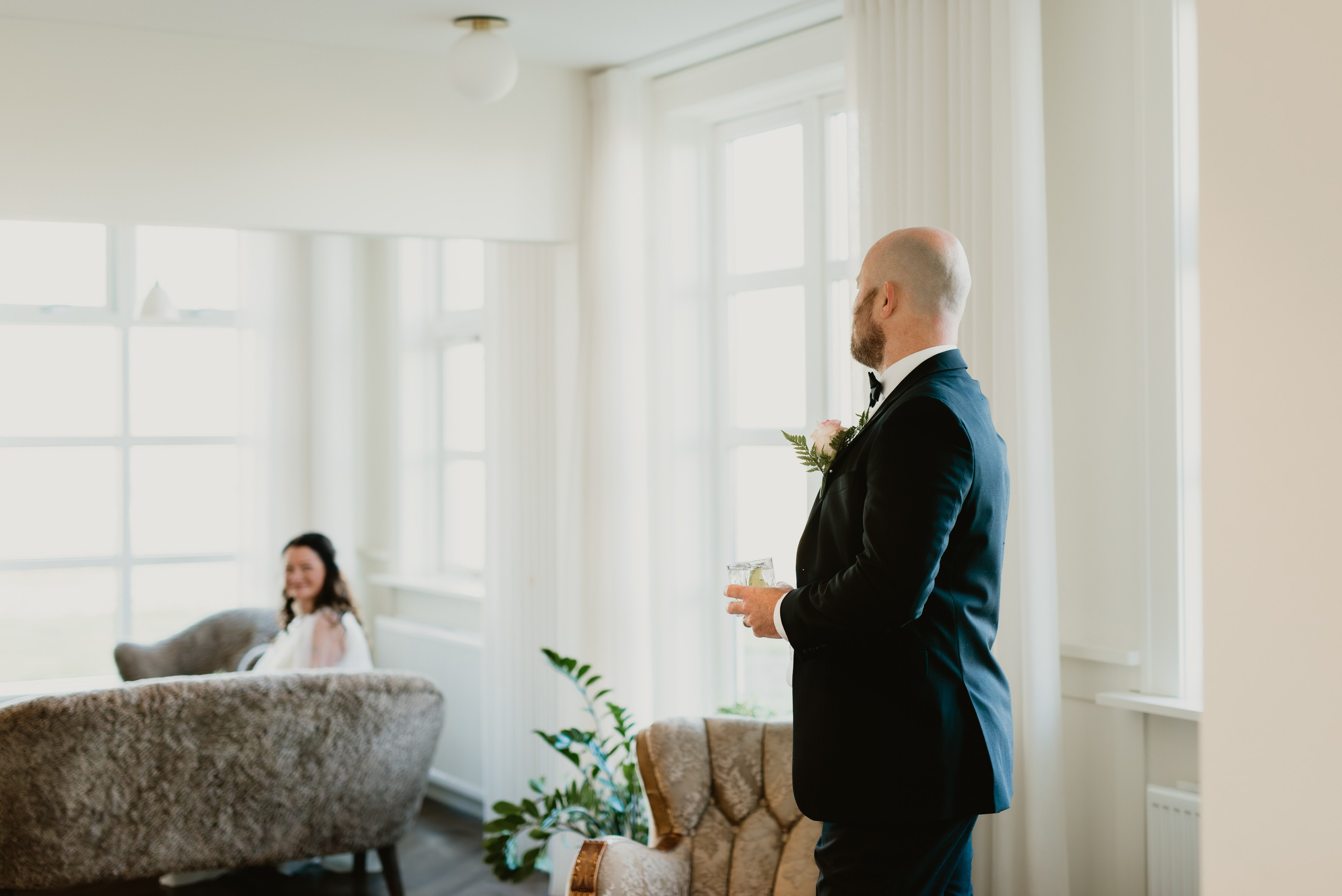 Intimate embrace between the bride and groom near the black church of Búðir, framed by rolling hills and an overcast sky.