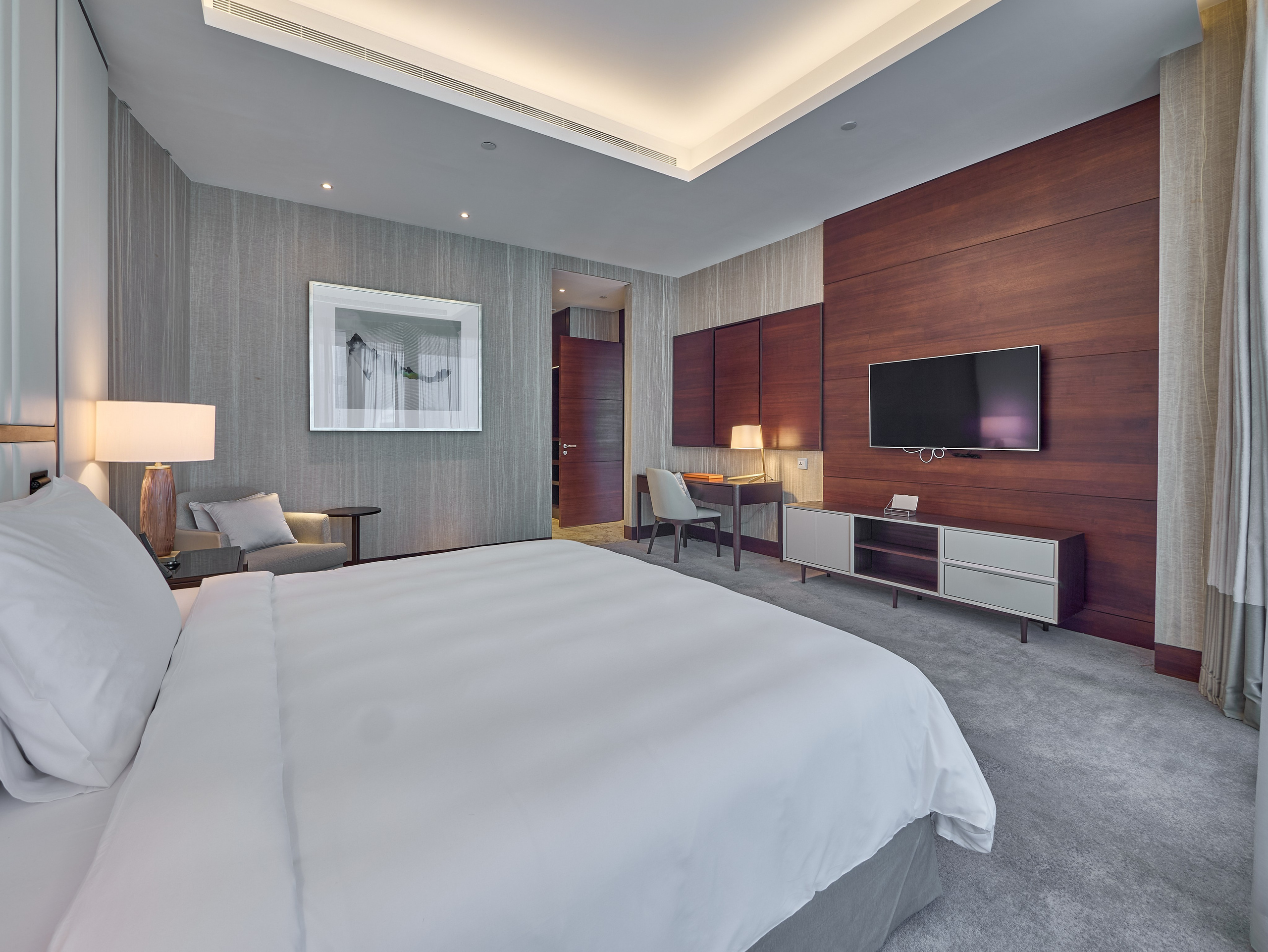 Stylish hotel bedroom featuring built-in media unit and warm wood accents — professional photography for vacation rentals and interior showcases.