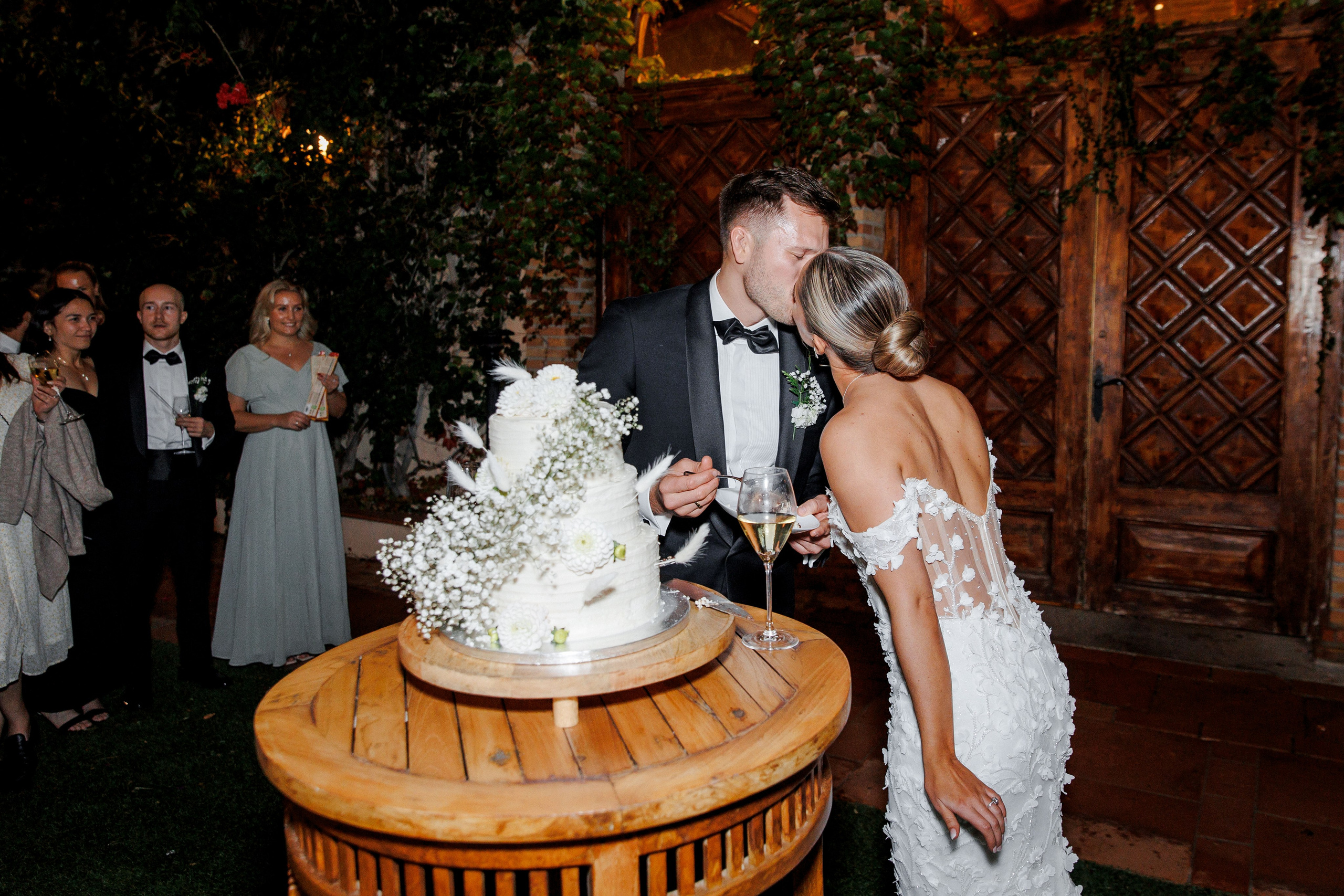 Wedding guests gathered around the couple during the cake-cutting ceremony at a Barcelona wedding, sharing in the joy.
