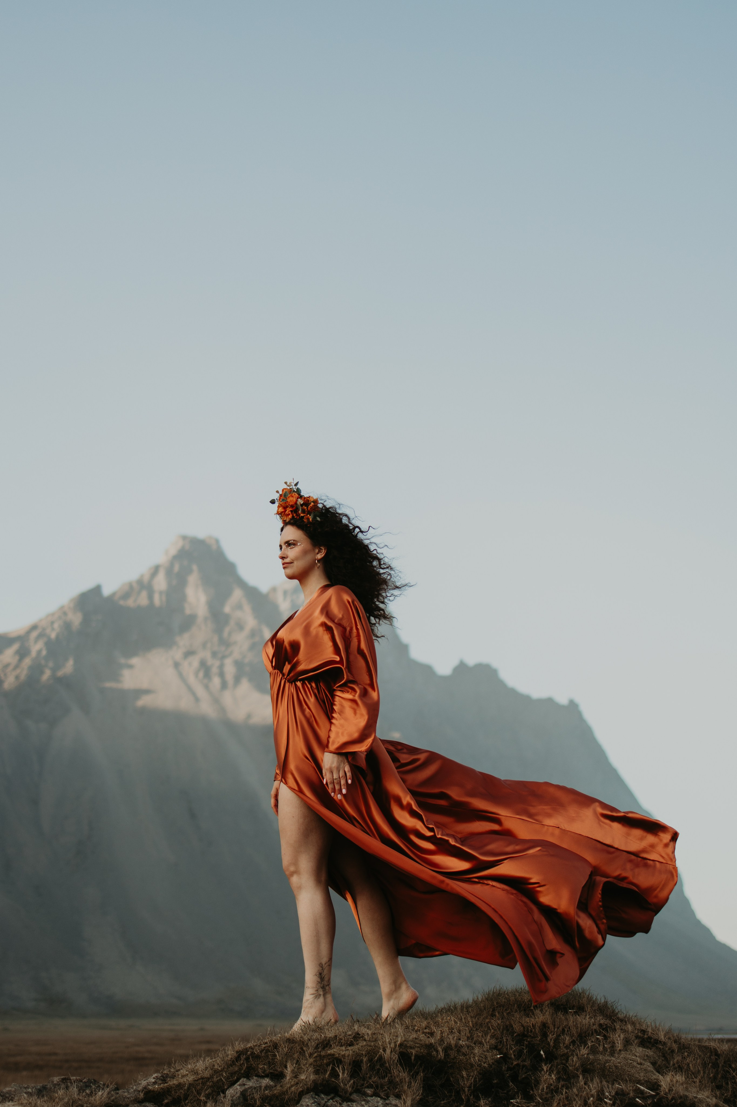 Woman embracing the elements—feminine outdoor portrait against Iceland’s rugged cliffs.