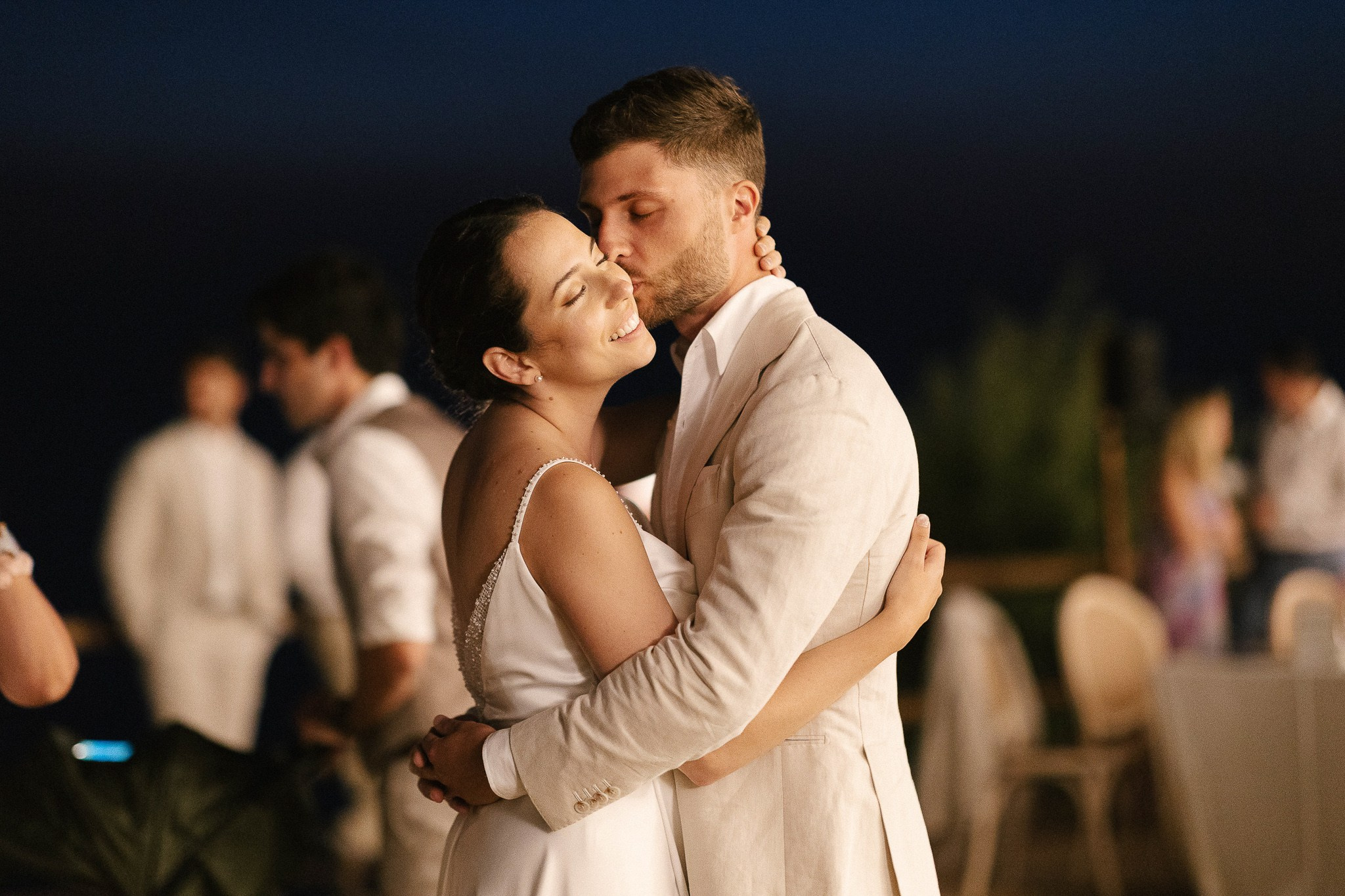 Groom kissing bride on the forehead during golden hour reception at Son Marroig, Mallorca luxury wedding celebration