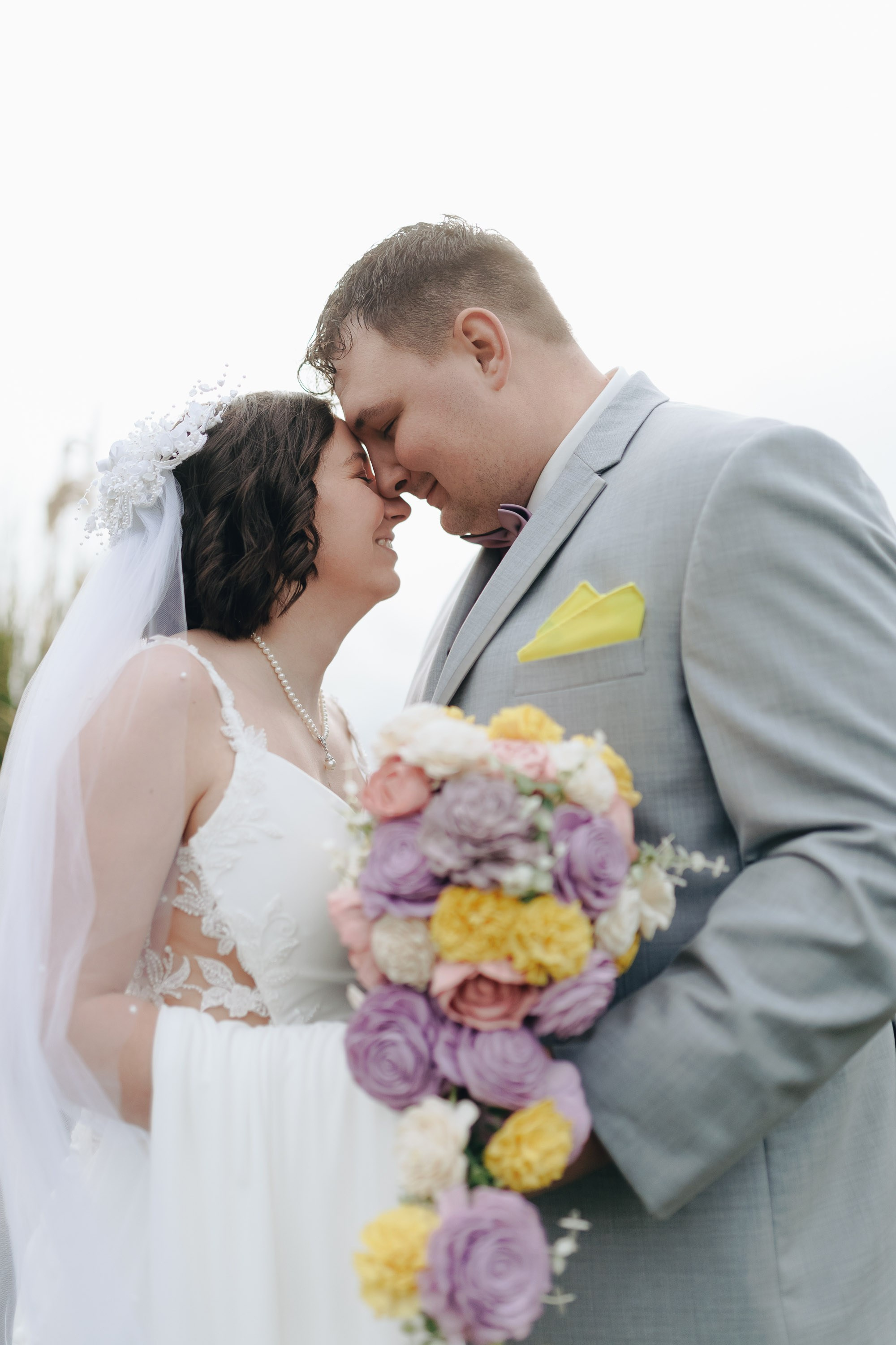 Bride and groom holding bouquet, intimate close-up