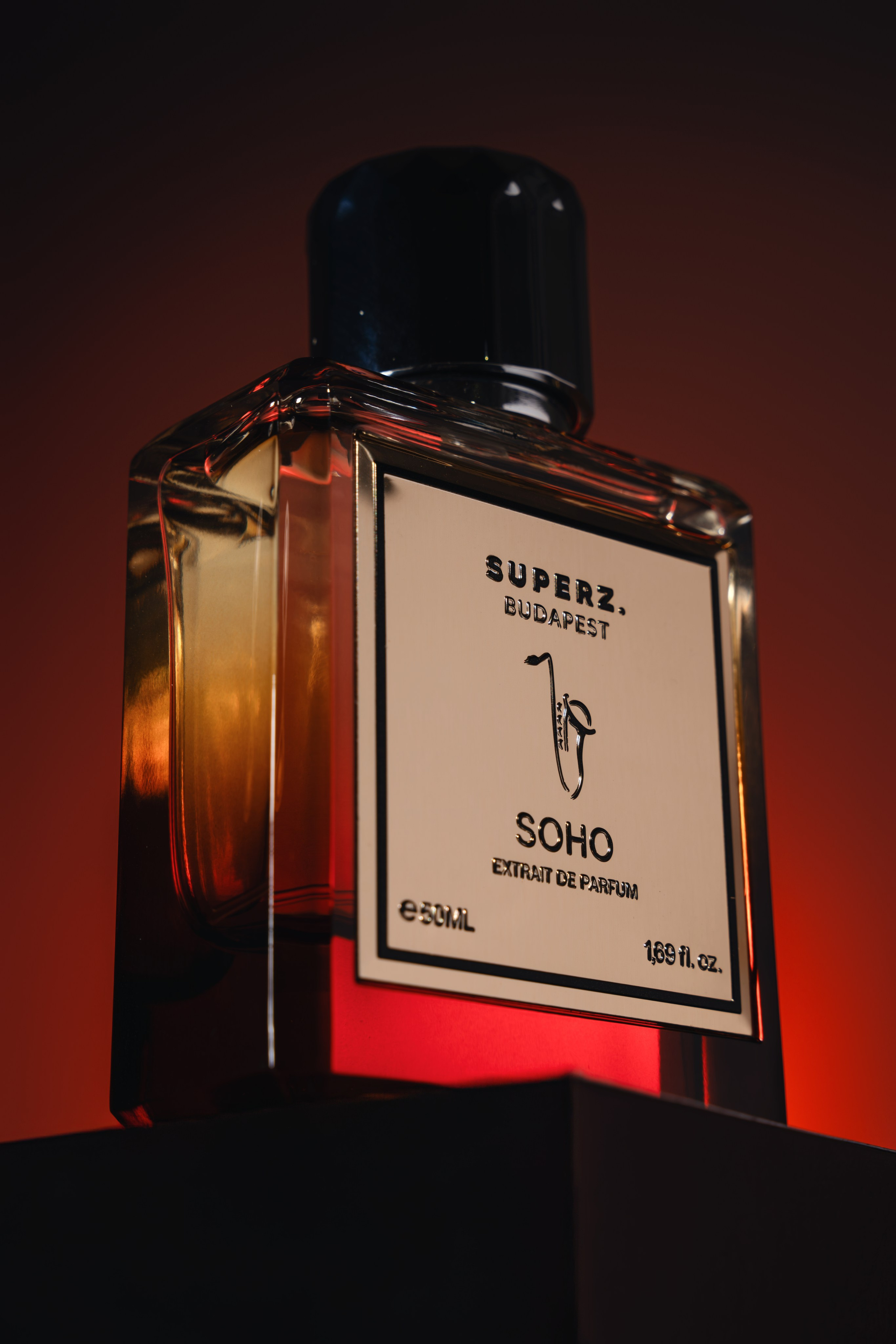 Editorial fragrance bottle close-up with golden amber glow — luxury perfume photography London studio.