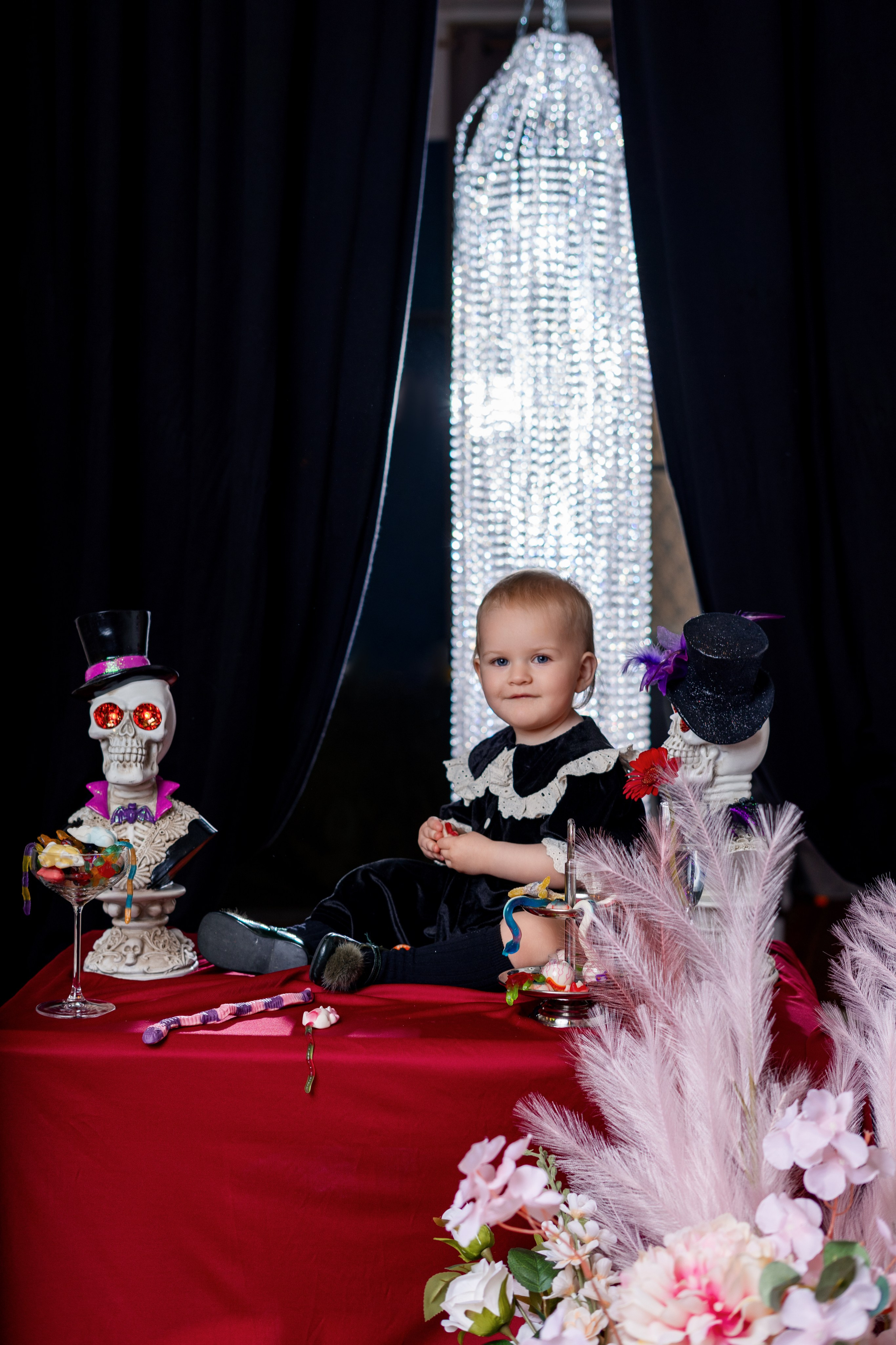 Enfant dans un décor Halloween sombre avec bougies et fleurs	•	Portrait artistique d’enfant dans une ambiance Halloween élégante	•	Enfant à table avec décoration Halloween et éclairage dramatique studio à roanne