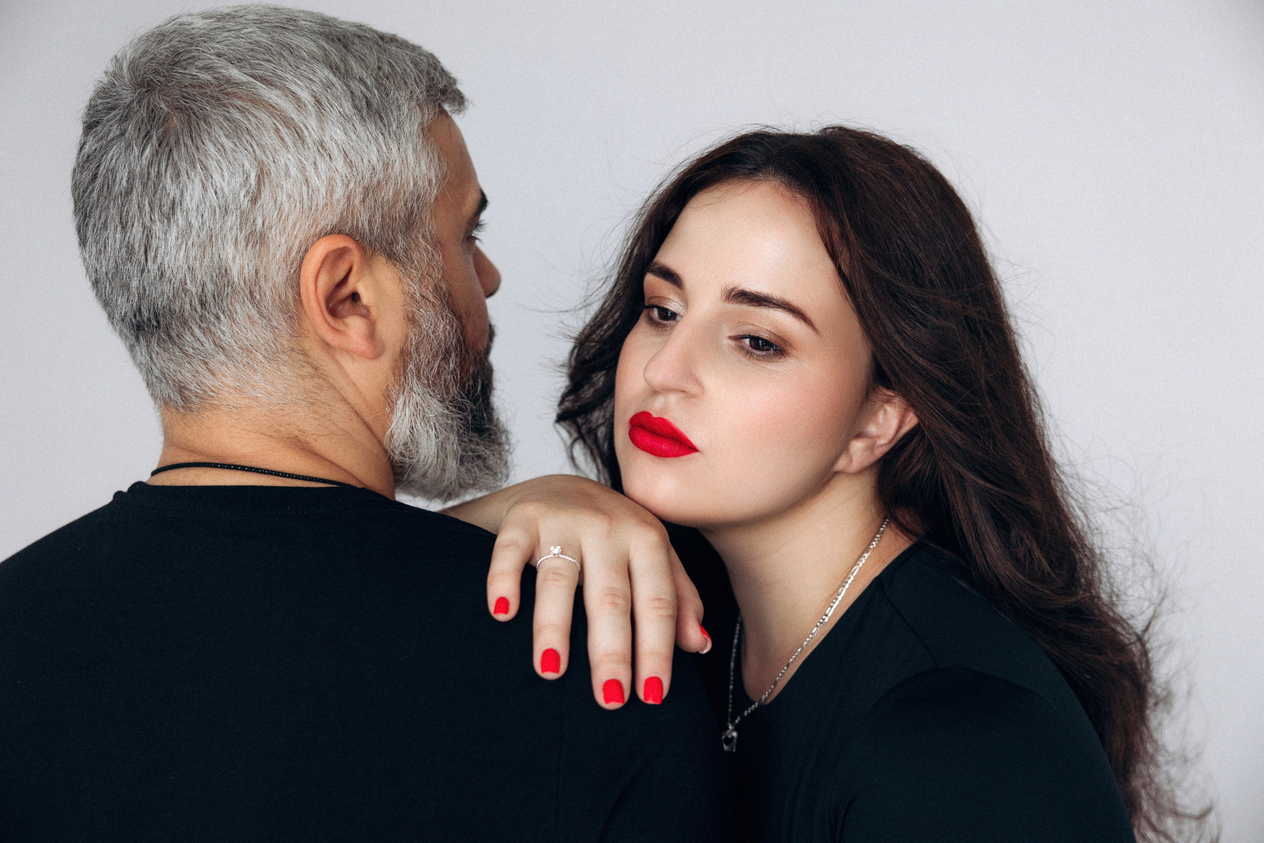 Zmysłowy portret pary – zbliżenie pełne napięcia, kobieta z ręką na ramieniu partnera, ciążowa elegancja.