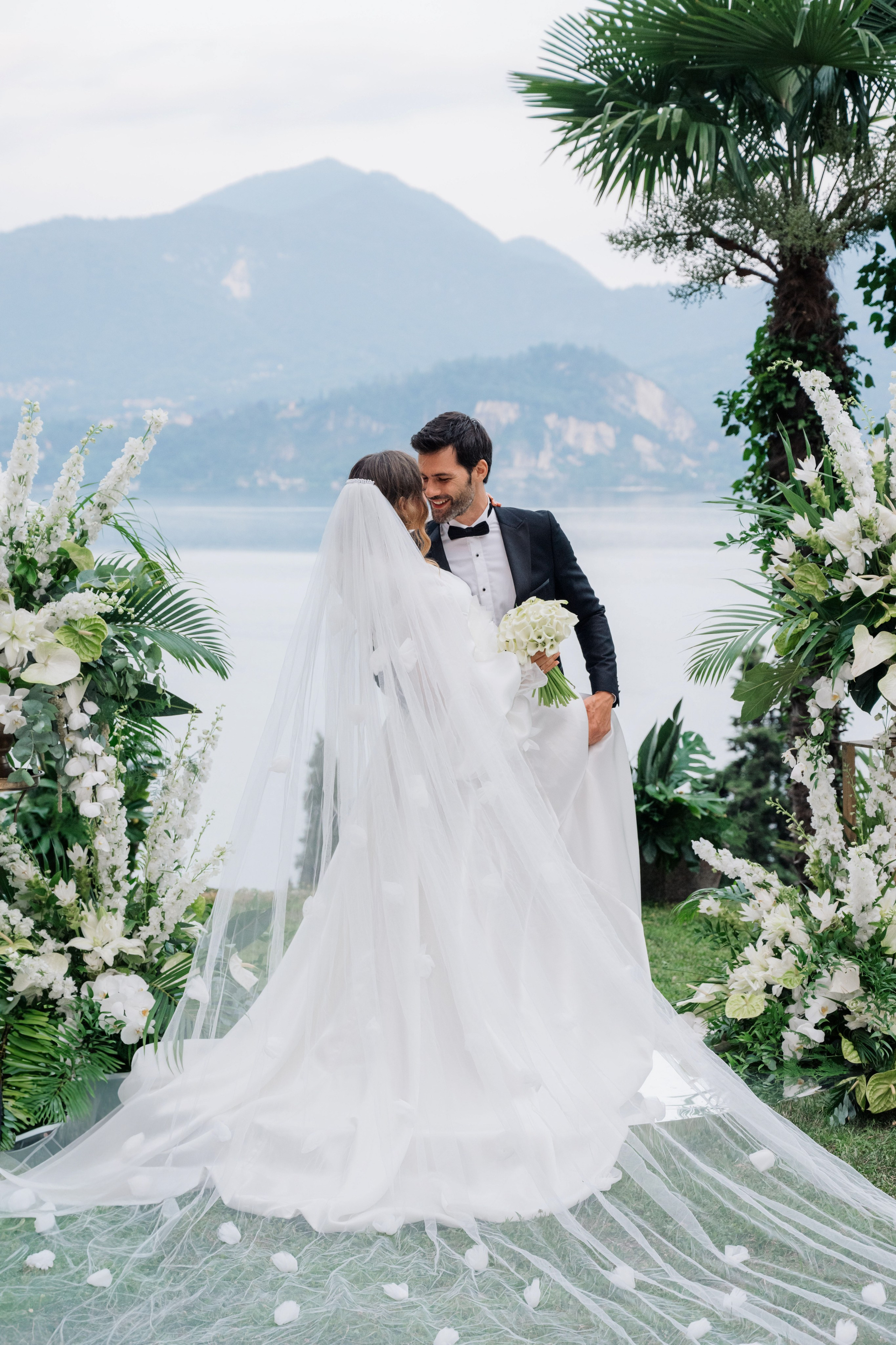 a bride and groom kissing in front of a floral arch