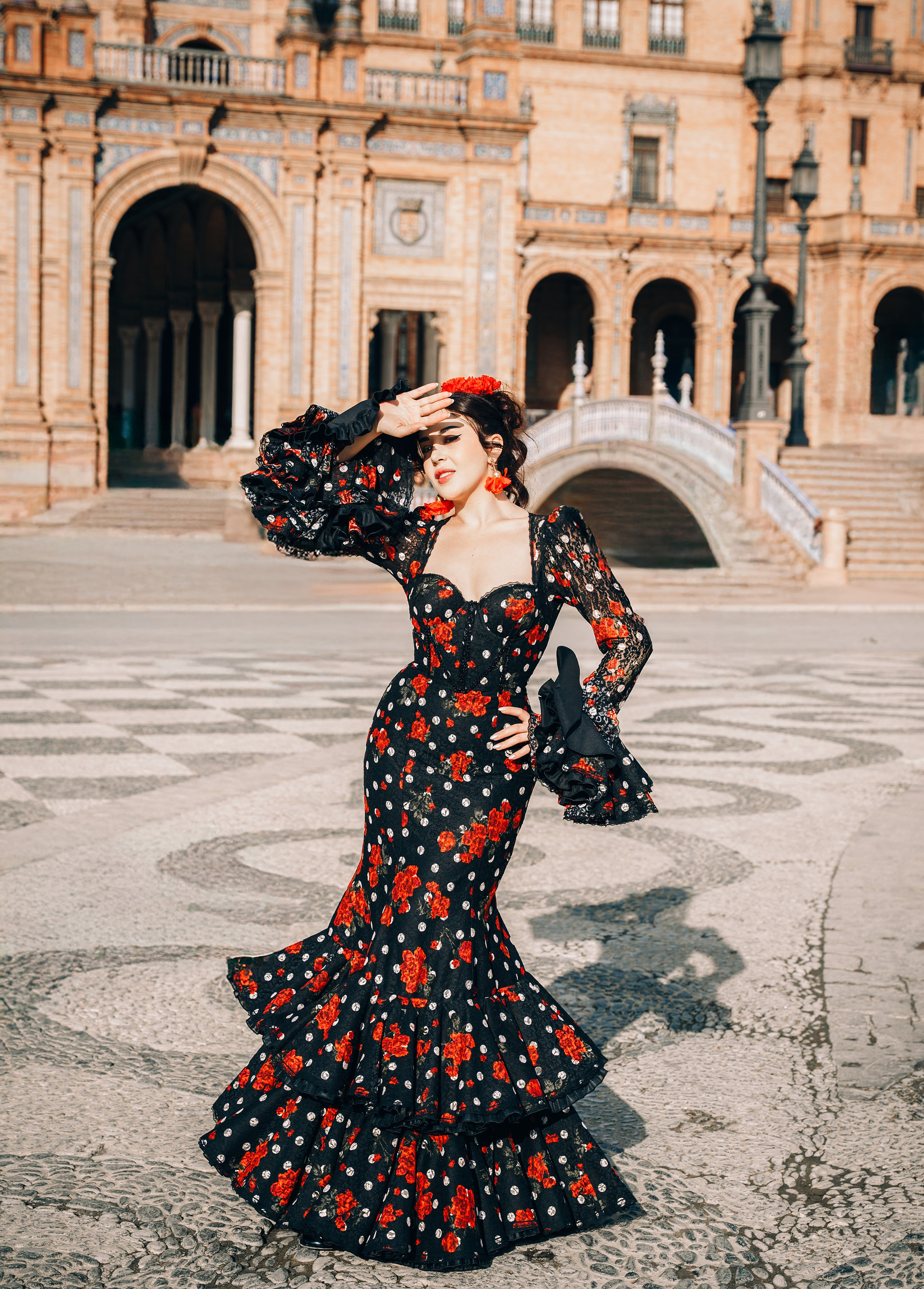 Элегантный портрет в стиле фламенко женщины в чёрно-красном платье с цветочным узором на площади Испании в Севилье, Испания — отличный пример для культурных и модных портретных фотосессий в Севилье и южной Испании.
