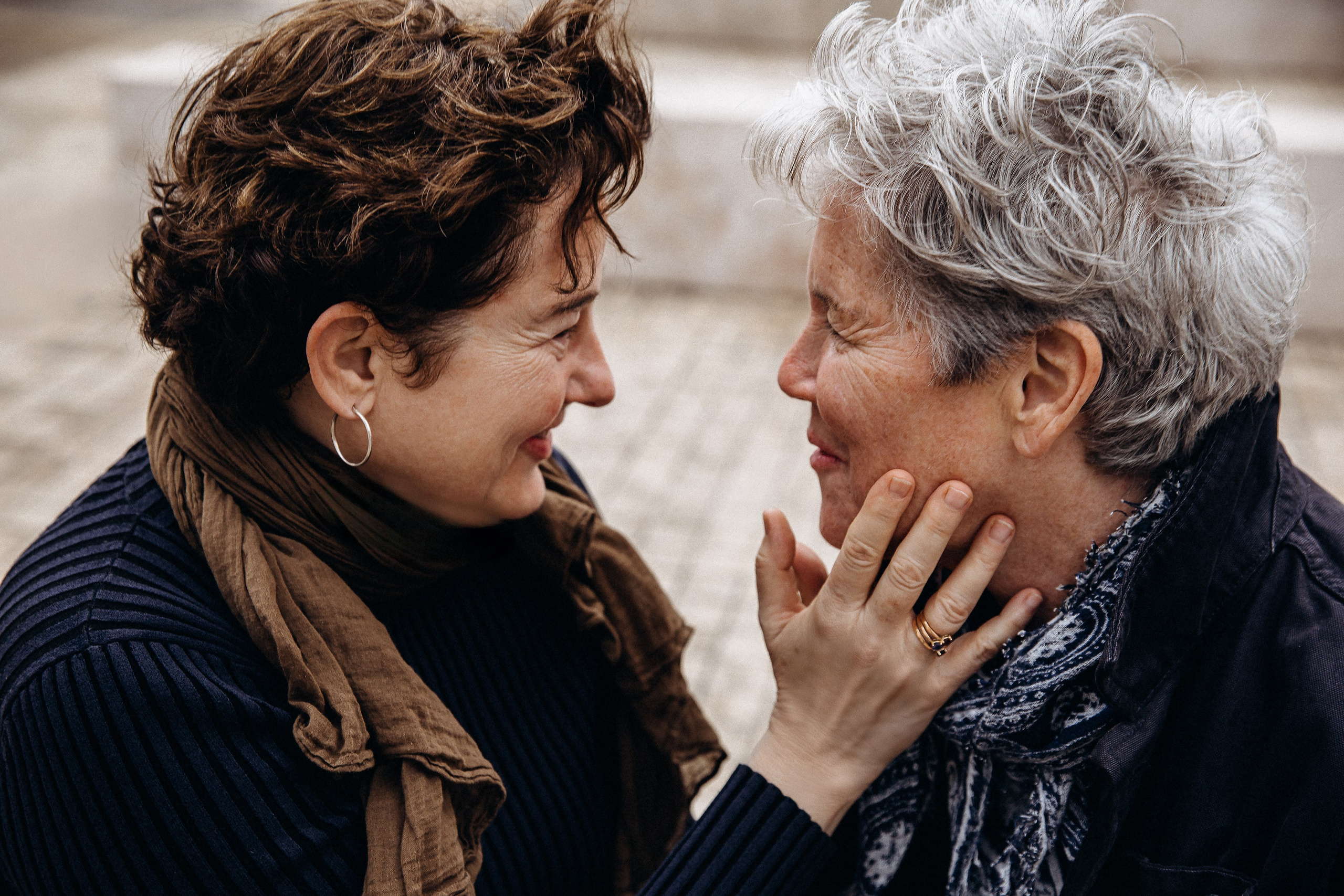 Семейная фотосессия в Валенсии, Испания, где две женщины делят тёплый эмоциональный момент, улыбаясь и касаясь лиц друг друга, снято в мягком естественном свете для искренней и интимной семейной связи — идеально для семейных фотосессий в Валенсии и по всей Испании.
