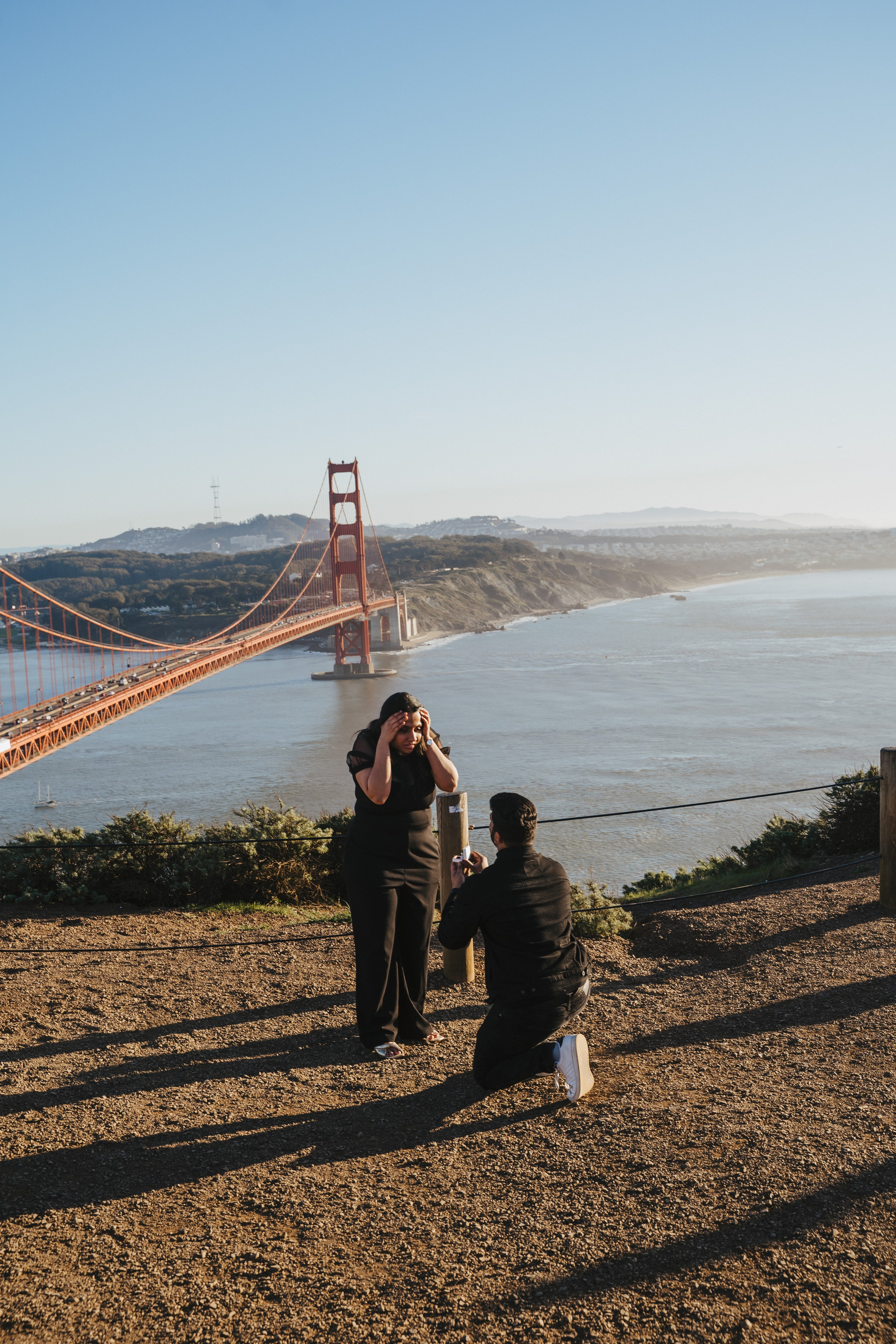 Proposal.  Overlooking the golden San Franisco Bridge sunset with a couple. Photographer Video. 