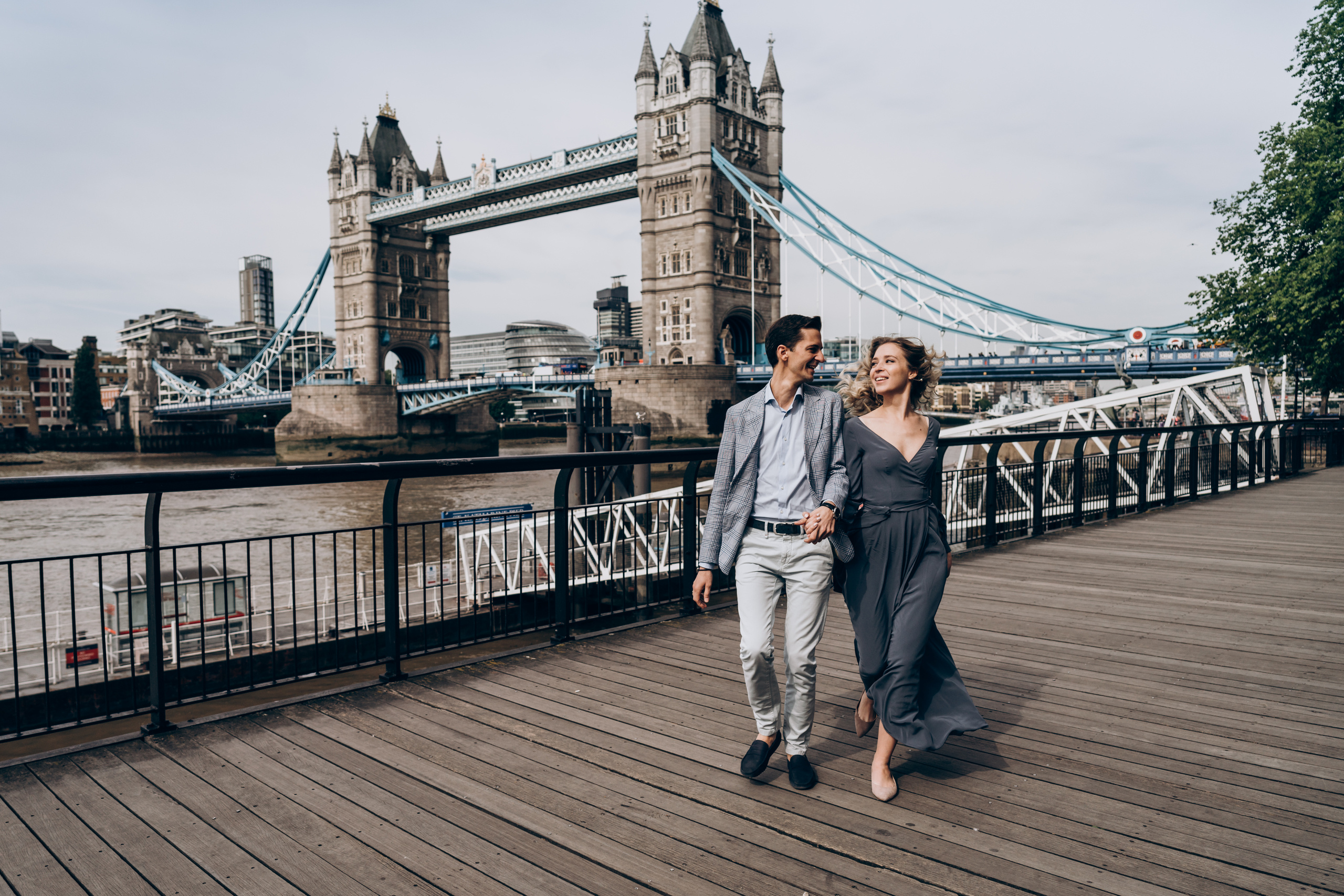 happy couple running together with Tower Bridge on the background 
