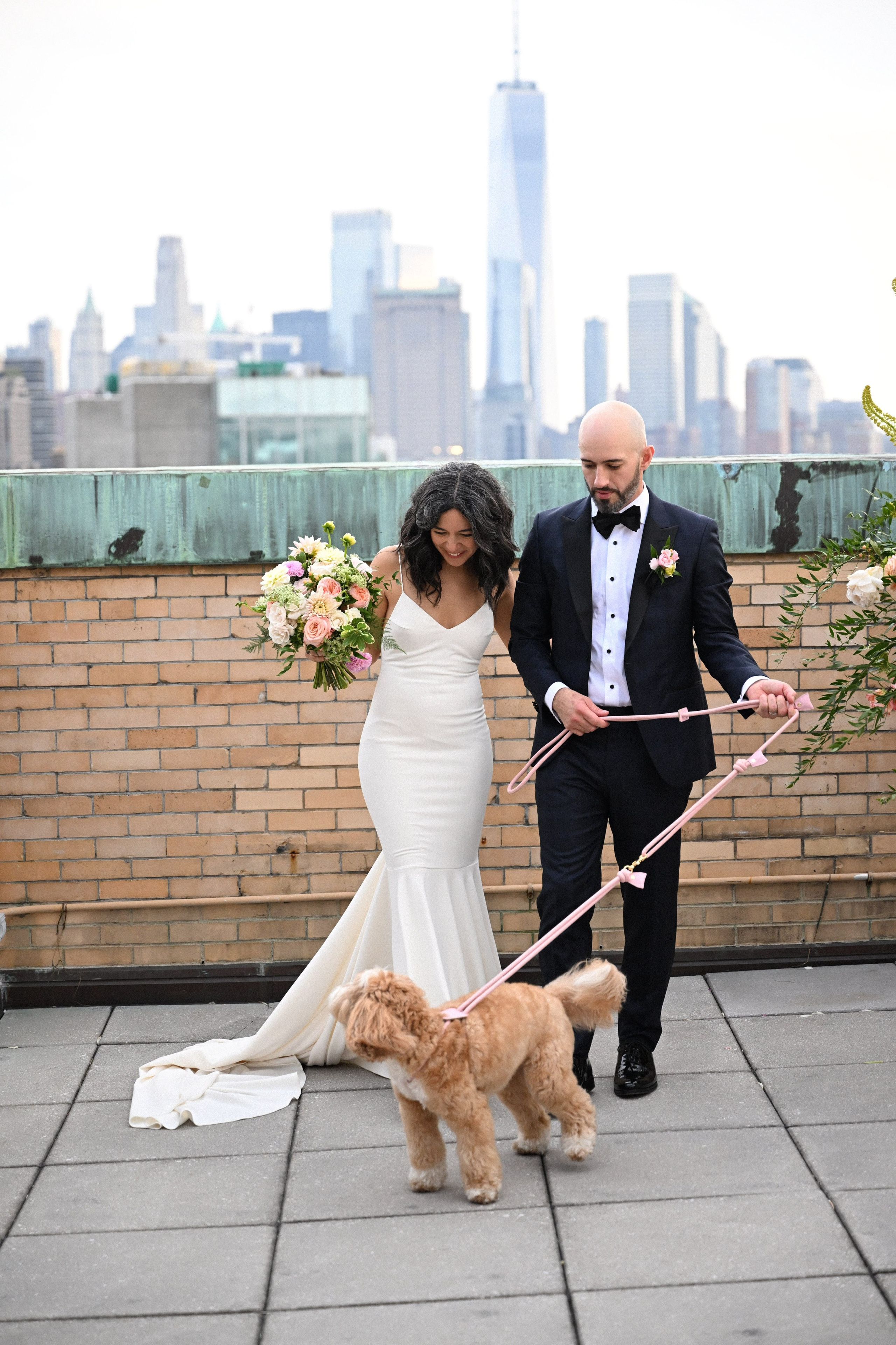 a bride and groom walking their dog on a rooftop