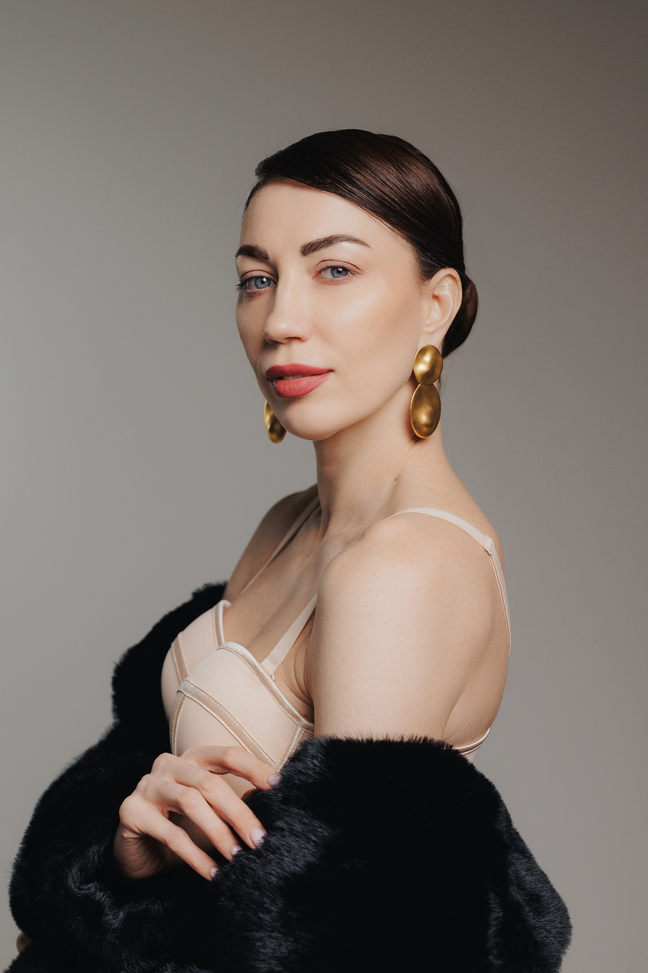 Minimalist editorial studio portrait of a woman with elegant posture and soft dramatic light against a neutral background, photographed in Leipzig, Germany. Минималистичный редакционный студийный портрет женщины с элегантной позой и мягким драматичным светом на нейтральном фоне, снятый в Лейпциге, Германия.
