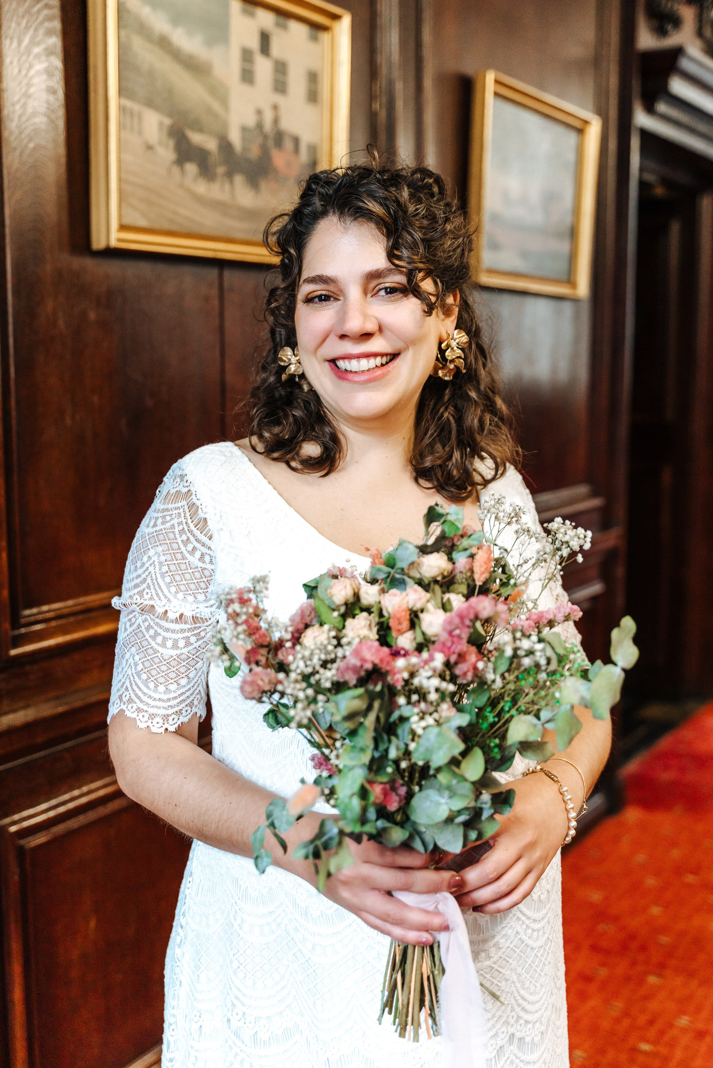Virginia holding her bridal bouquet in a white lace wedding dress at Henley-on-Thames Town Hall.