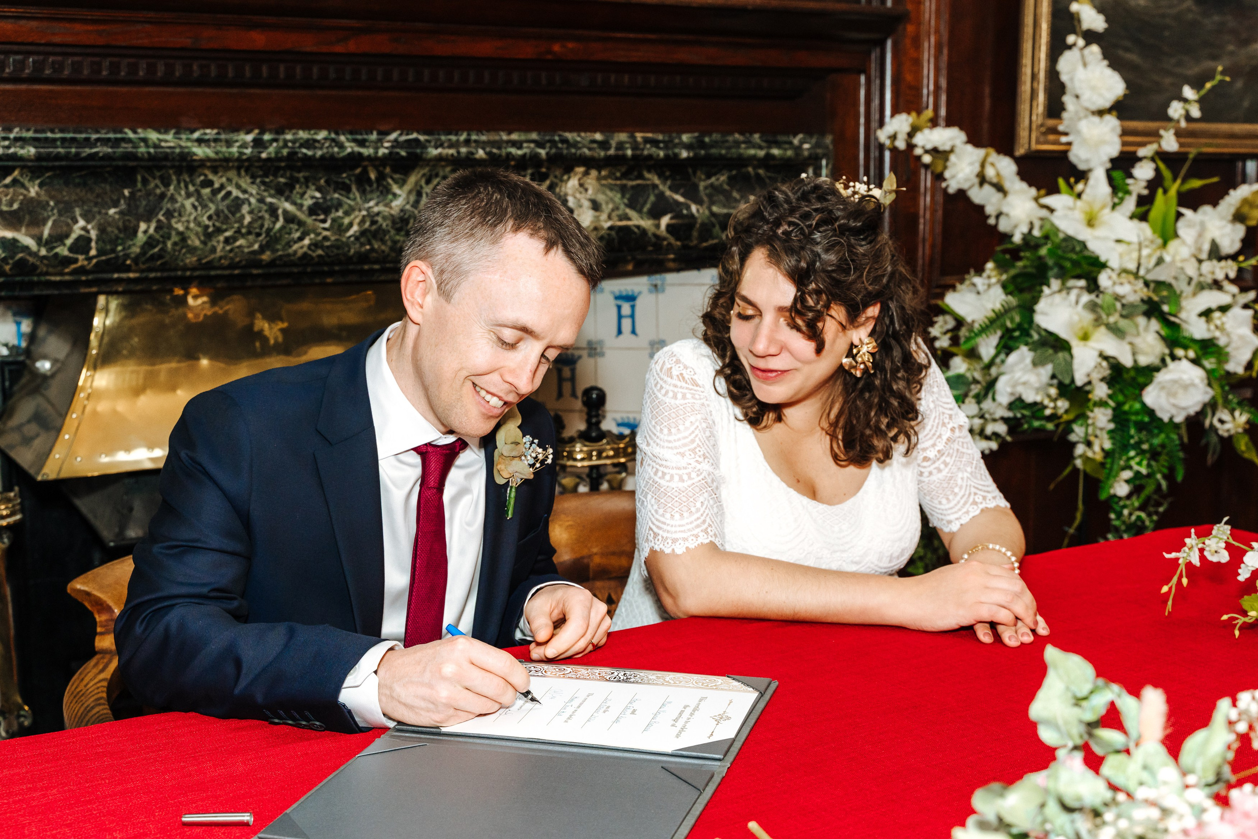 Groom Peter signing the marriage register beside his bride Virginia.