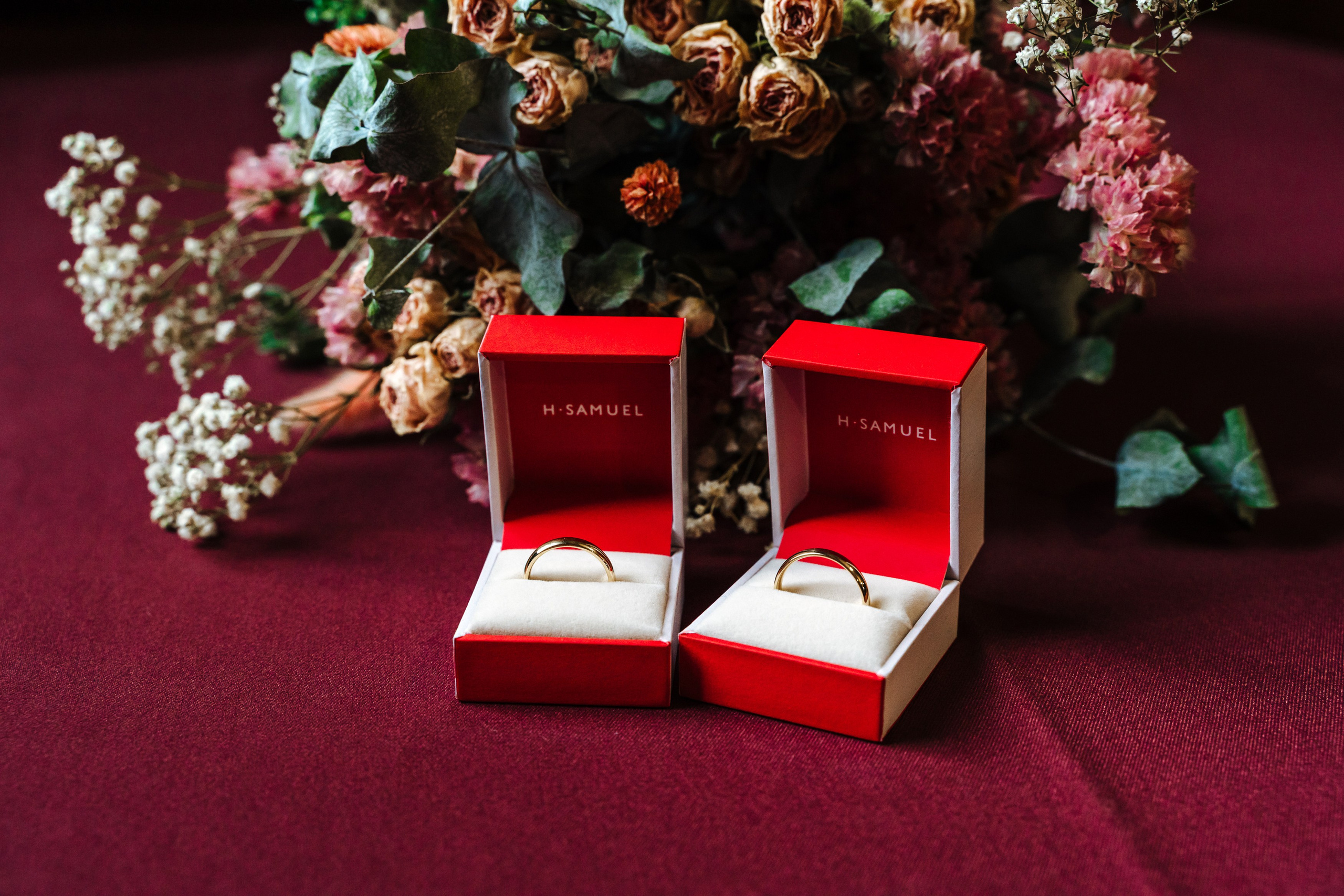 Gold wedding rings displayed in open red ring boxes at Peter and Virginia's wedding.