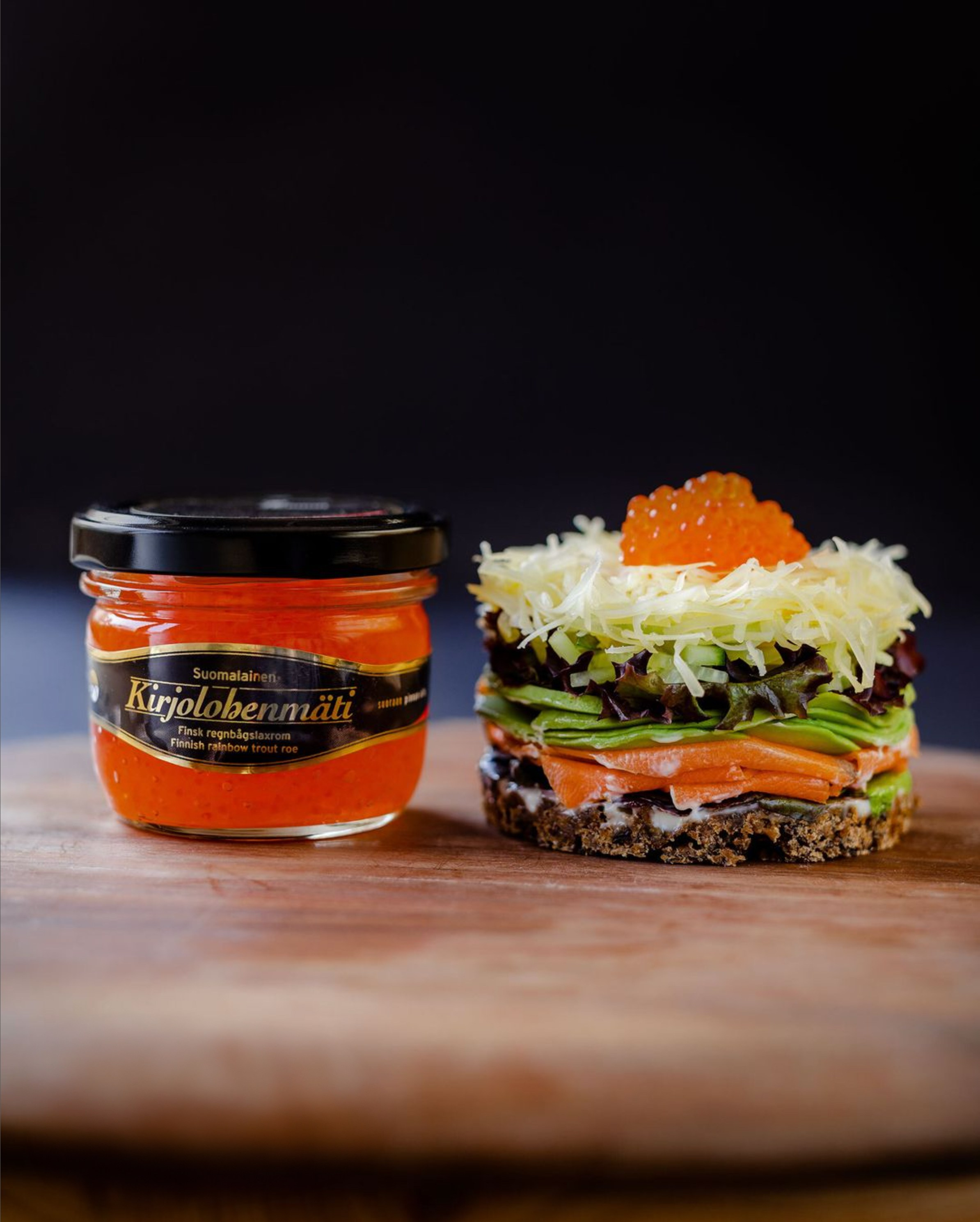 Kaunis kirjolohen caviar pienessä purkissa ja iso voileipä saaristolaisleivällä, lohella, avokadolla, salaatilla, juustolla ja mädillä. 