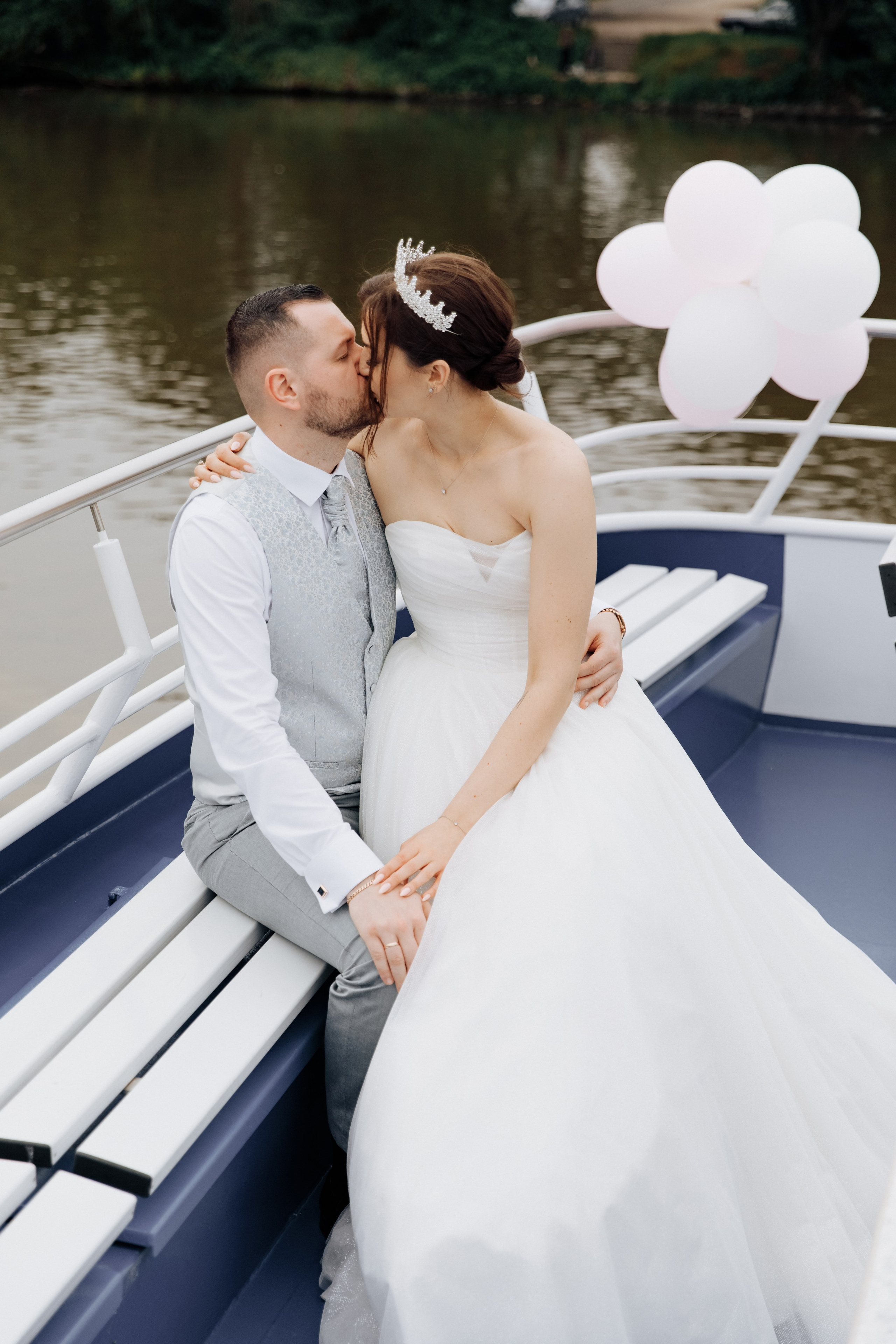 Die Braut sitzt auf dem Schoß des Bräutigams auf dem dekorierten Deck mit Luftballons.