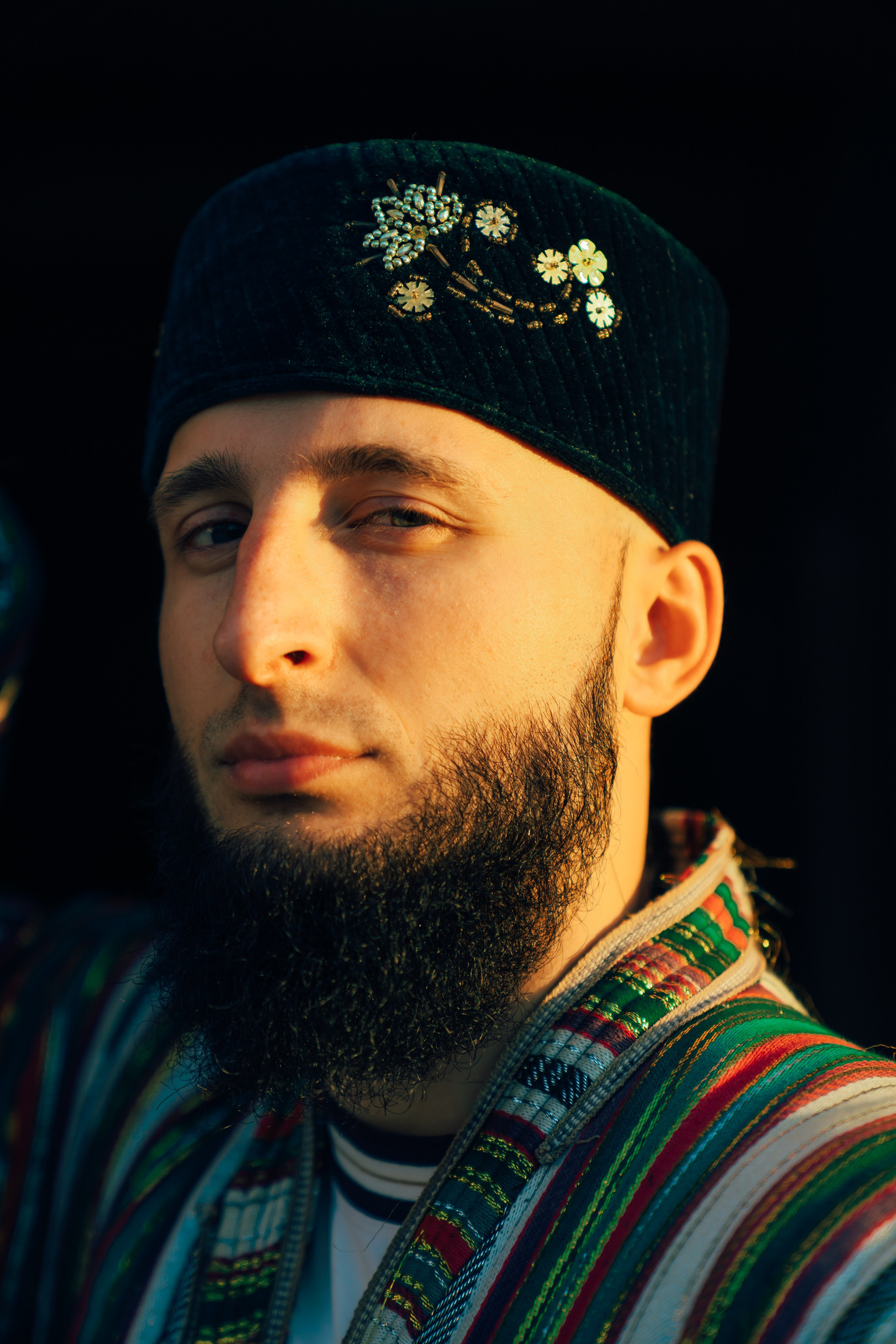 Портрет мужчины в узбекской тюбетейке и полосатом чапане Бекасам на фотосессии