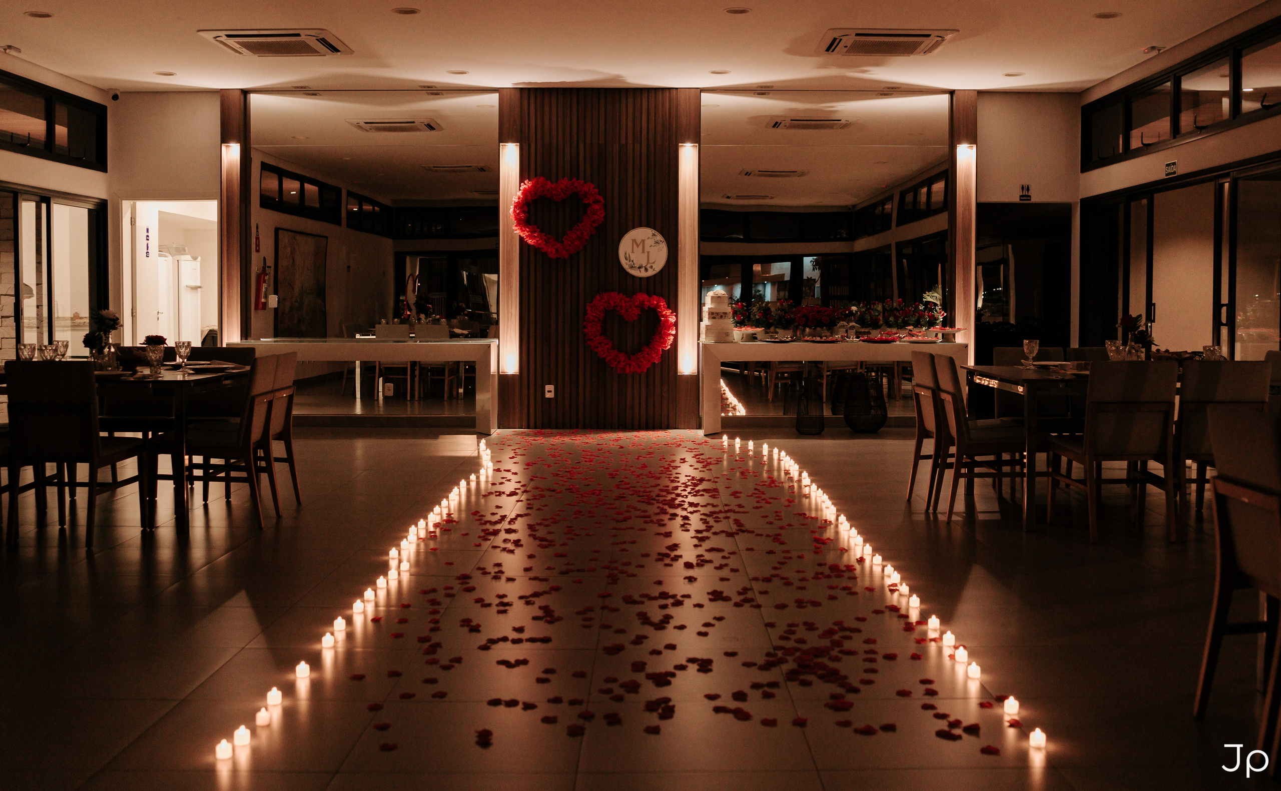 Corredor iluminado por velas formando caminho até o centro do salão.