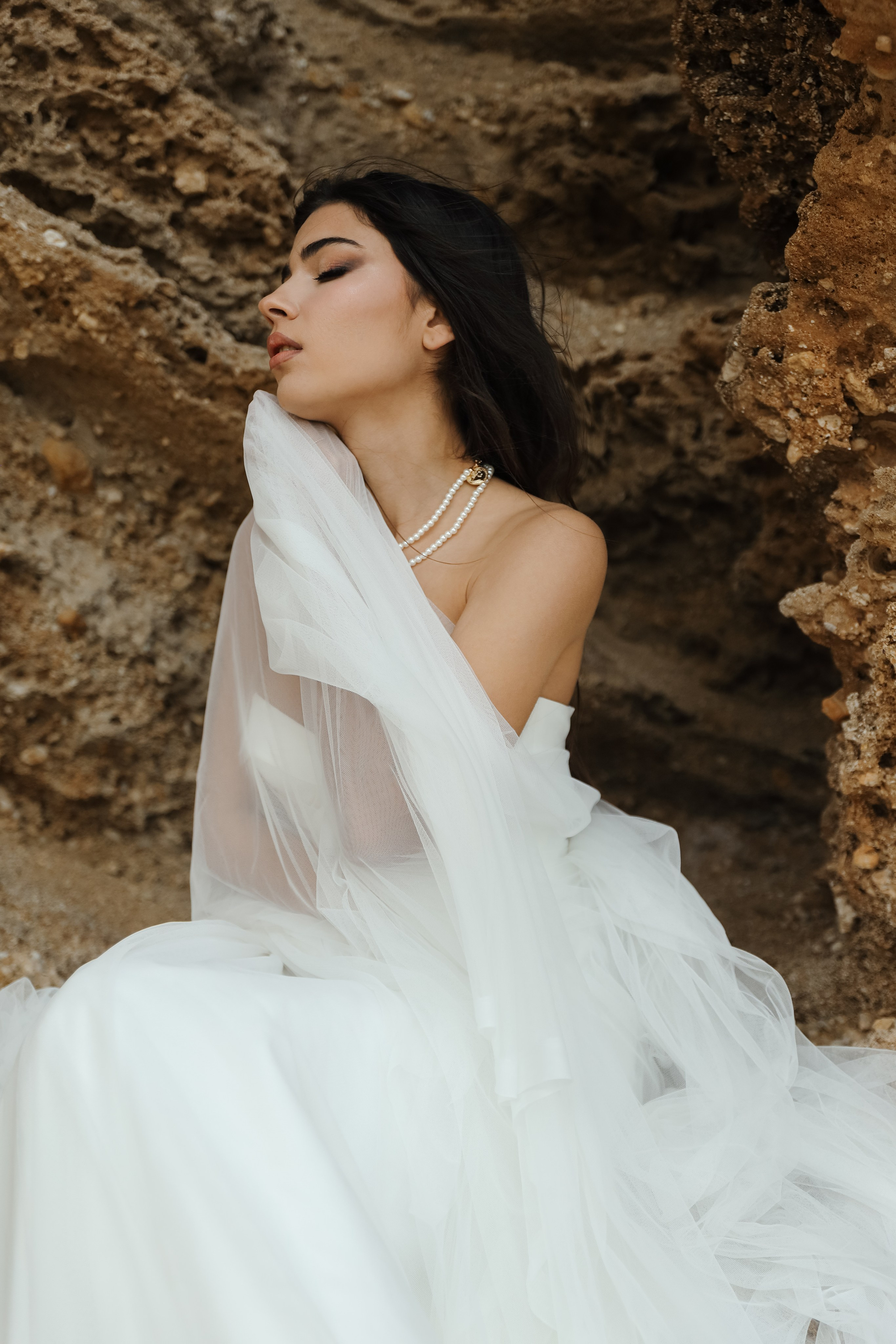 An art photo shoot of a girl in a wedding dress on the windy Kalithea beach in Rhodes, Greece