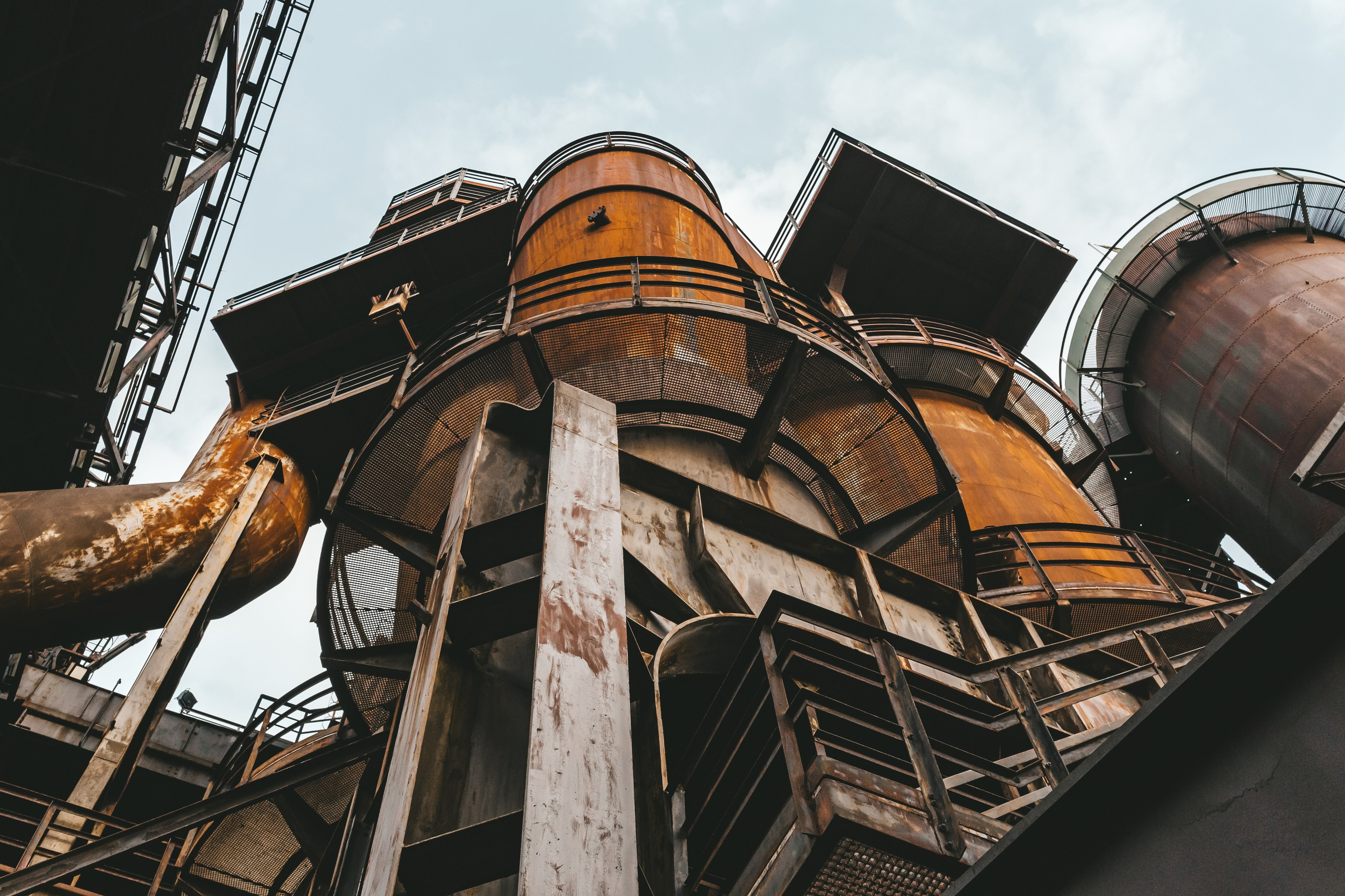 Лестницы и трубы, образующие сложную геометрию на фоне неба.