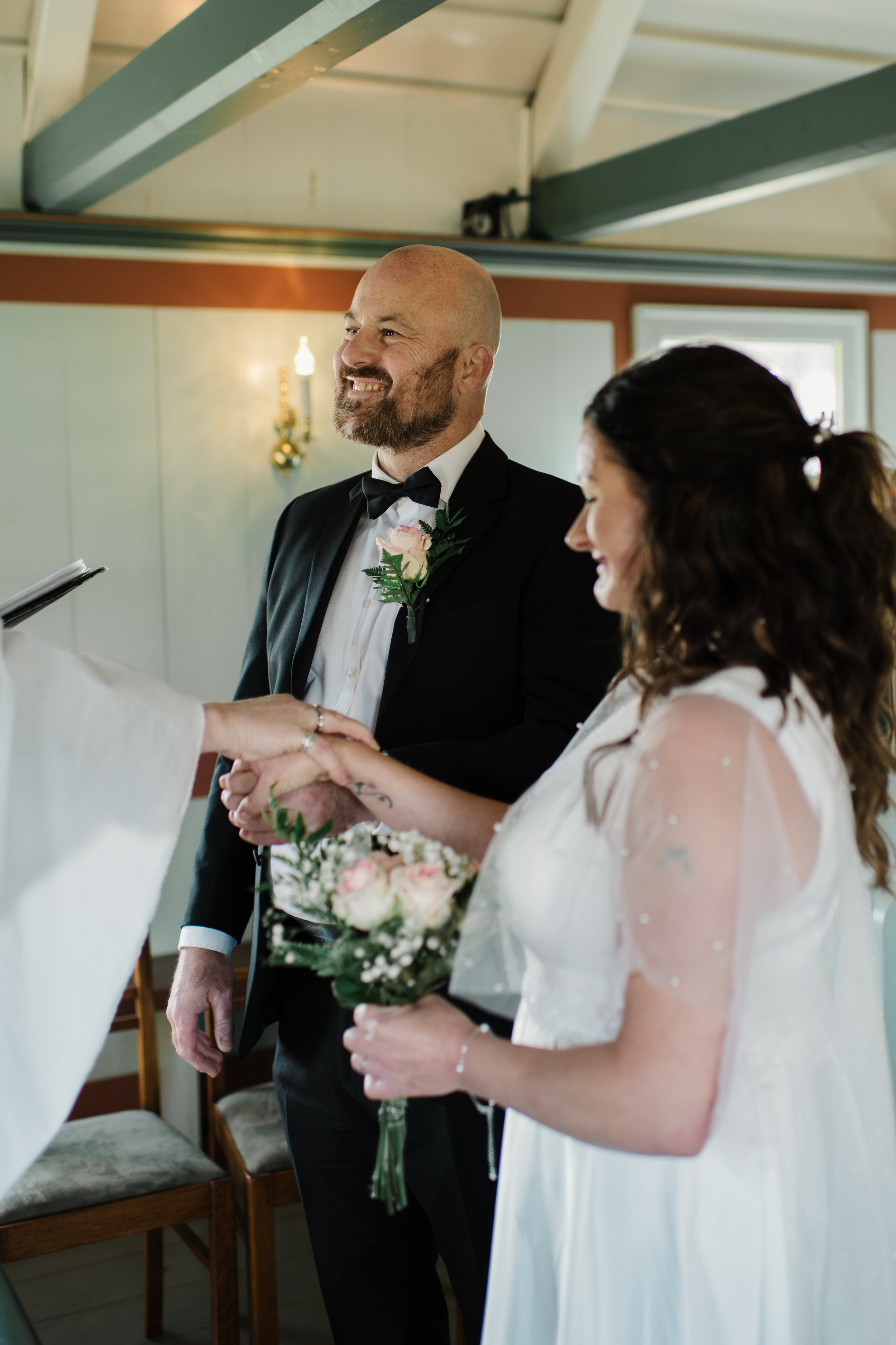 Newlyweds walking towards Búðakirkja, with the wild Icelandic coastline stretching behind them.