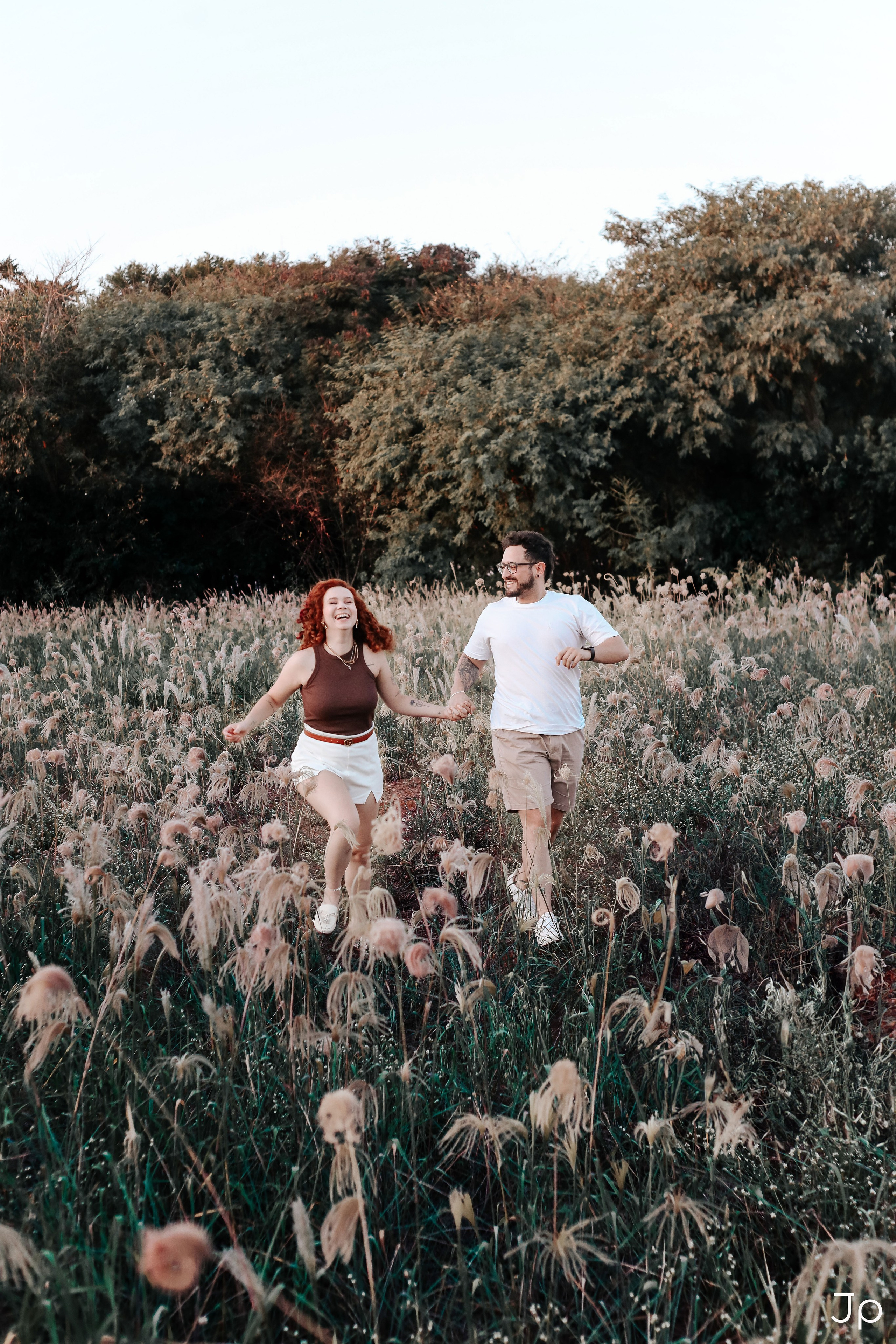 Casal caminhando no meio de um campo florido.