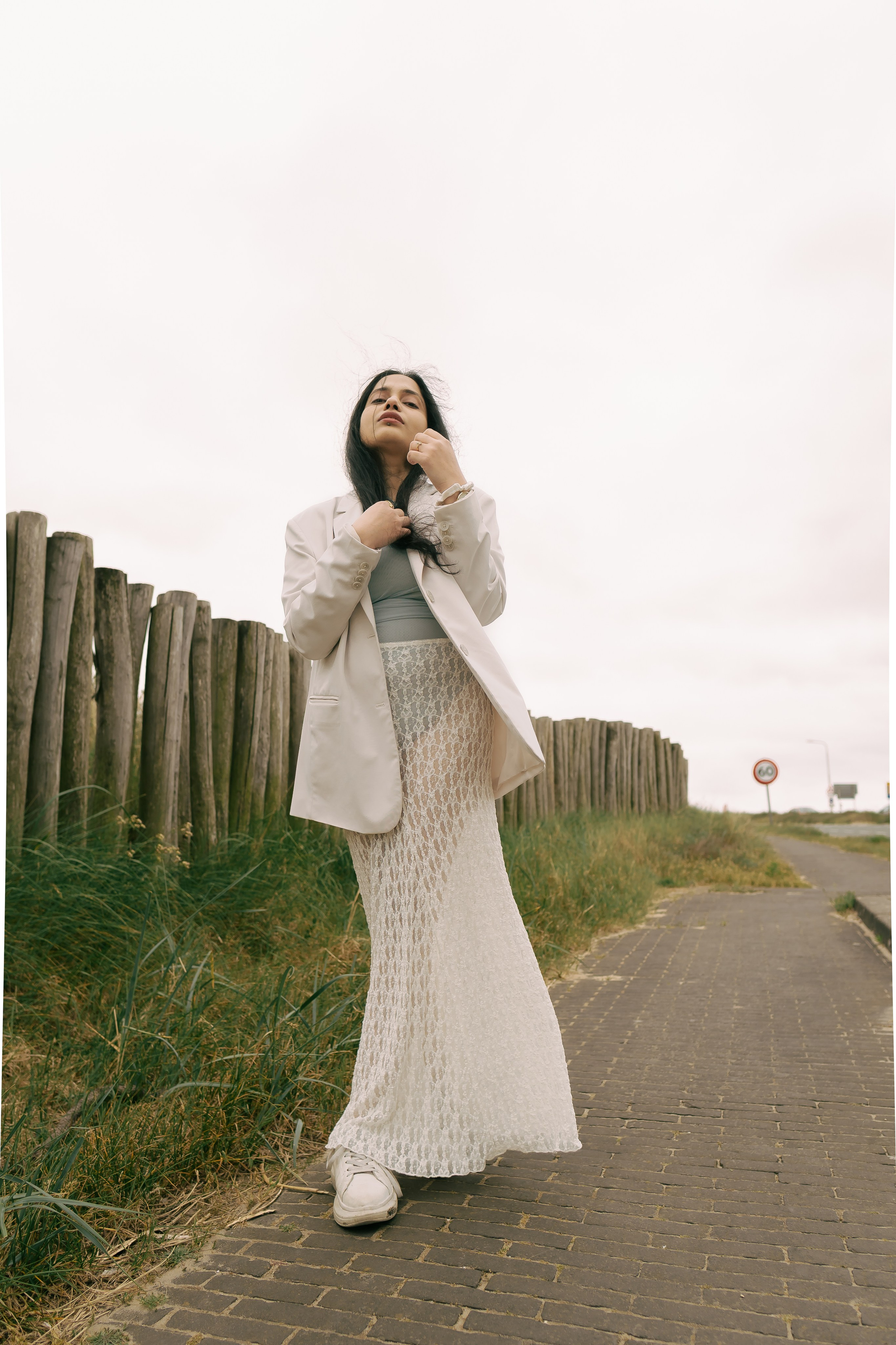 Fashion photoshoot in dunes with lace skirt and white blazer