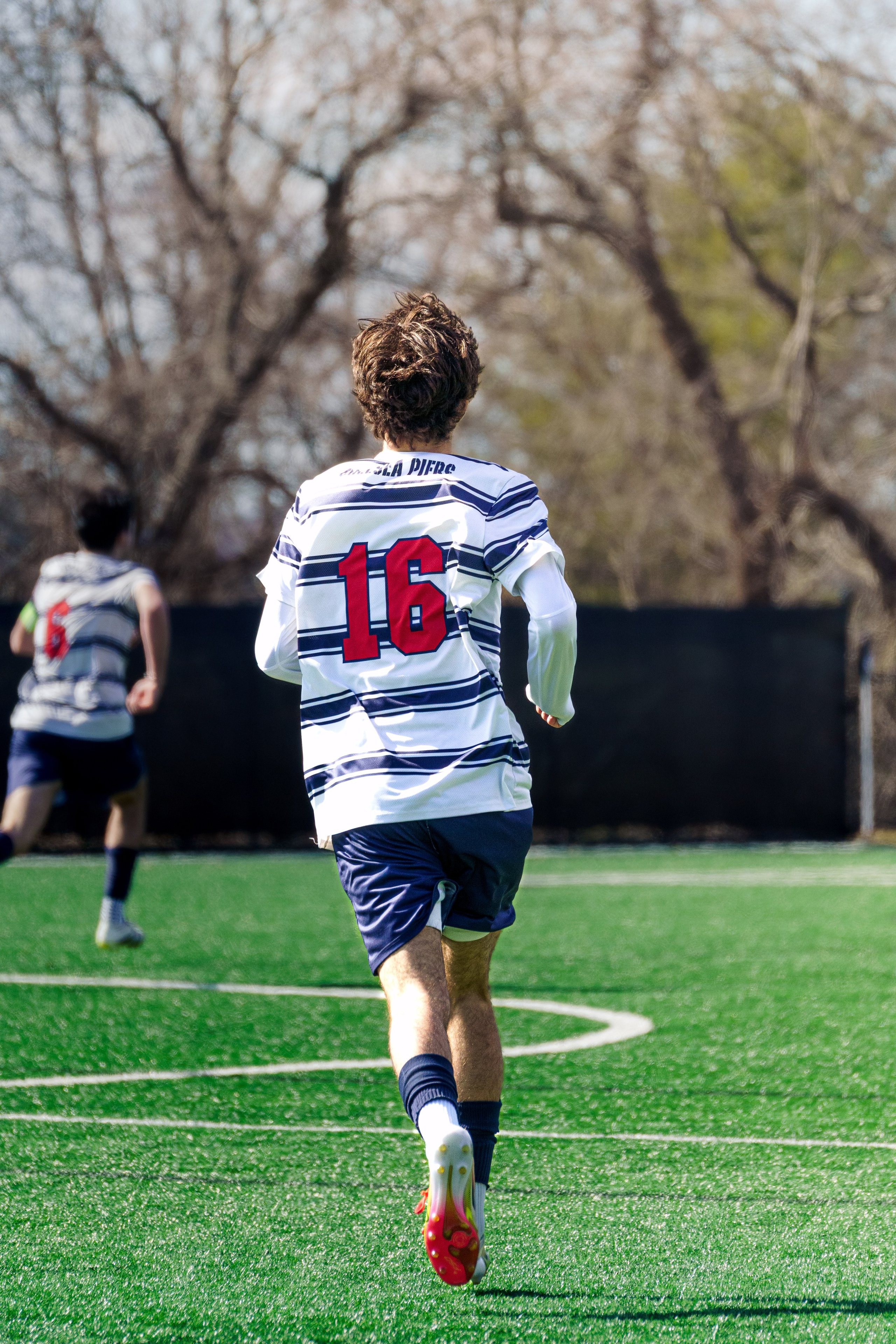 Rear view of a soccer player sprinting forward with his jersey number clearly visible on his back.