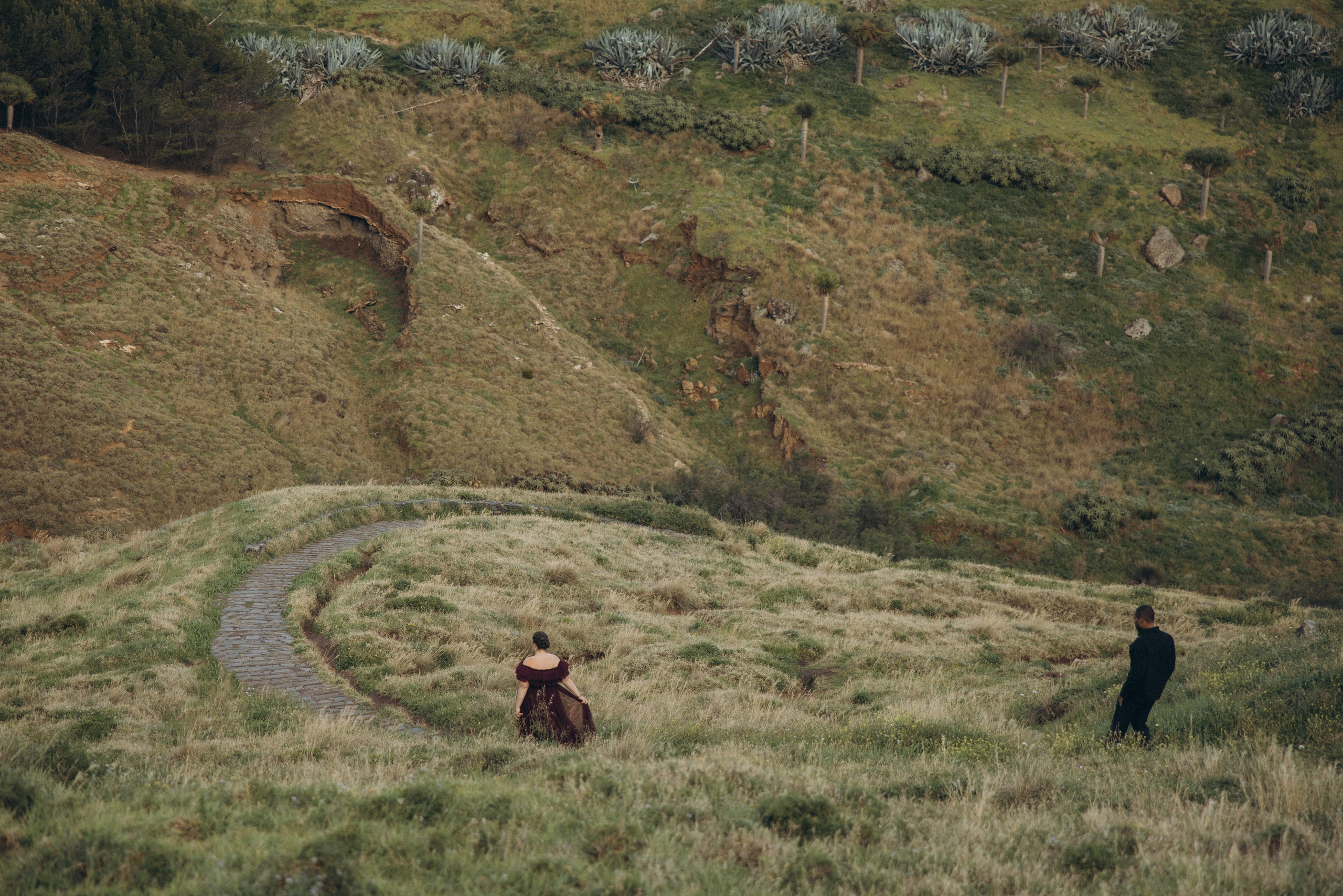 A glowing expectant mother standing on a cliff overlooking the ocean in Madeira, her dress flowing gently in the wind as the golden sunset casts a warm glow.