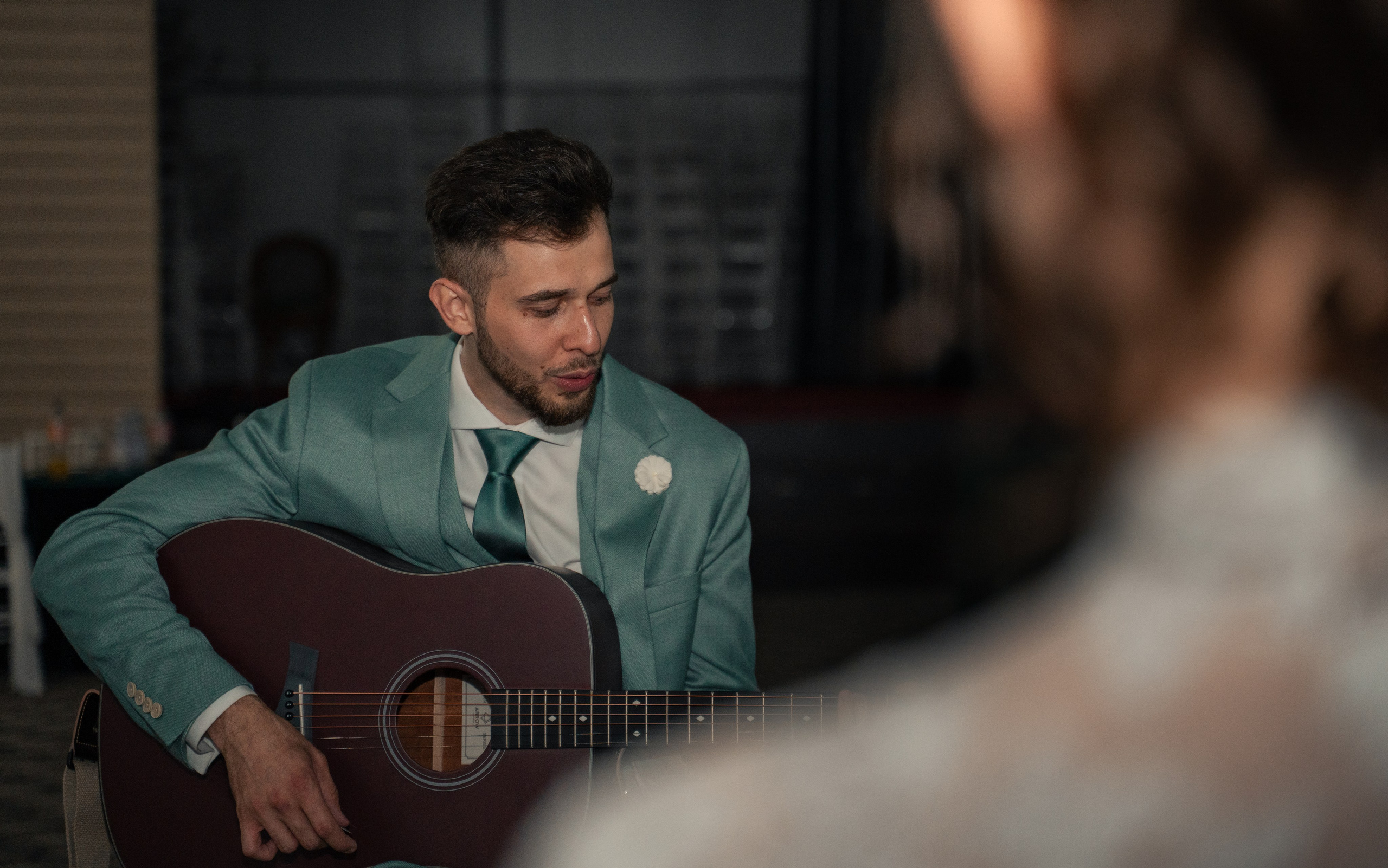 Mire cântând la chitară acustică în timpul petrecerii, privire concentrată, fotografie documentară de nuntă, incadru.ro.
