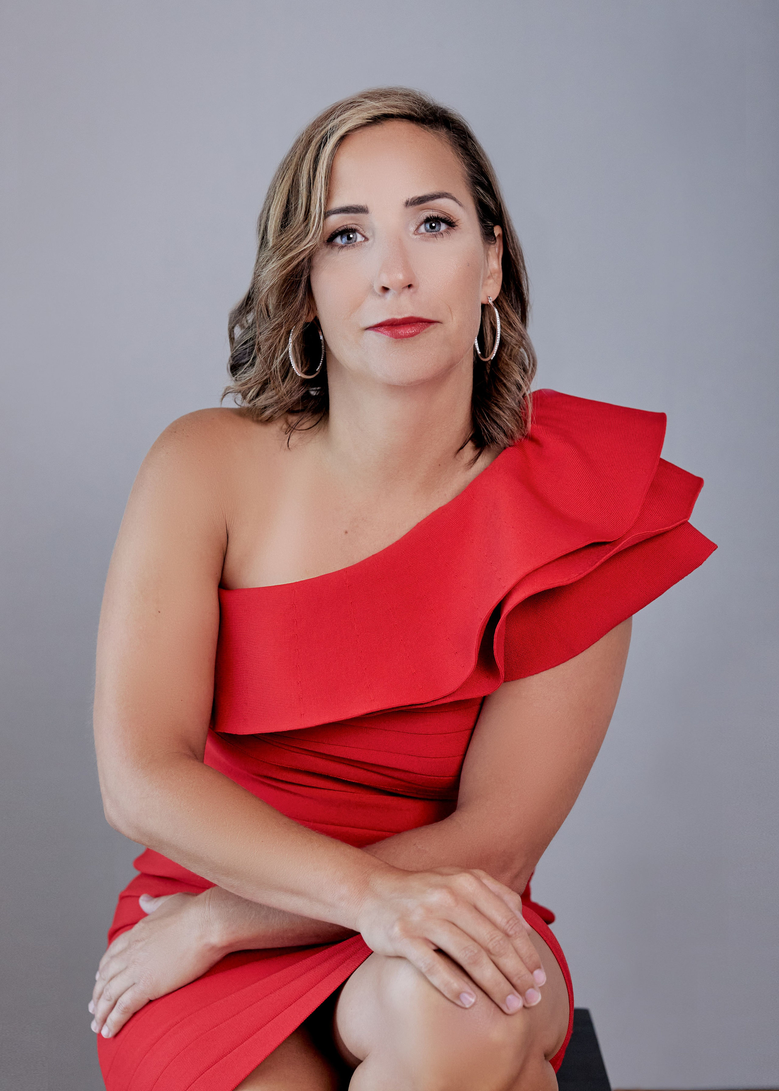 woman in red dress sitting on stool looking at camera 